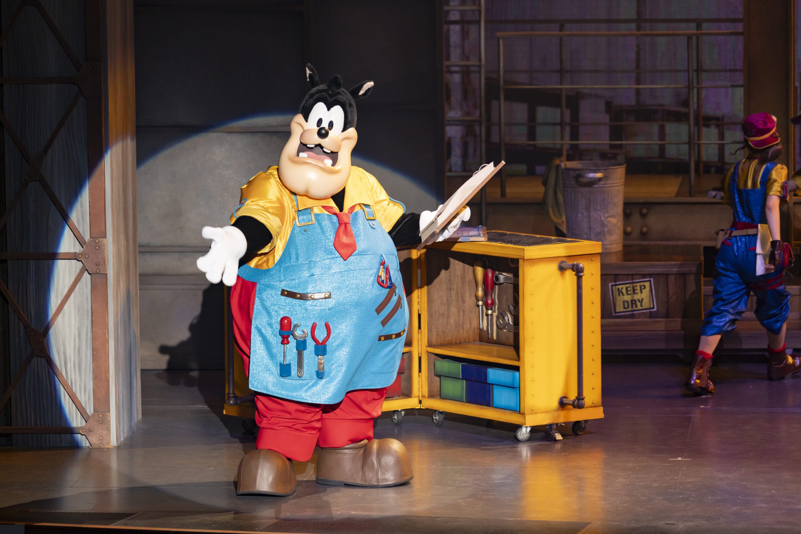 Pete from Disney, dressed as a handyman, stands on stage at Tokyo DisneySea with dreams take flight in the air.