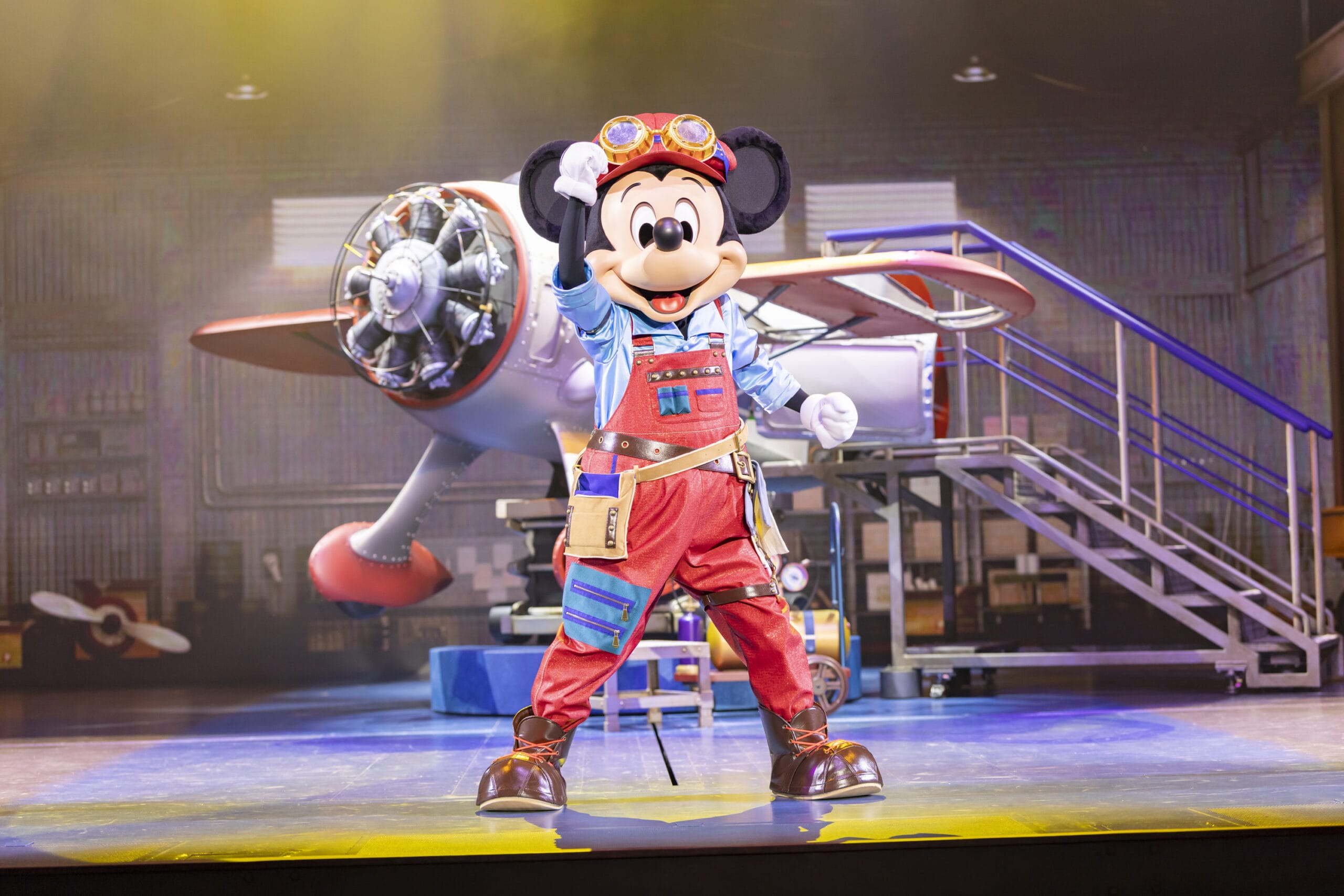 Mickey Mouse dressed as an aviator stands before an airplane at Tokyo DisneySea, where dreams take flight on stage.