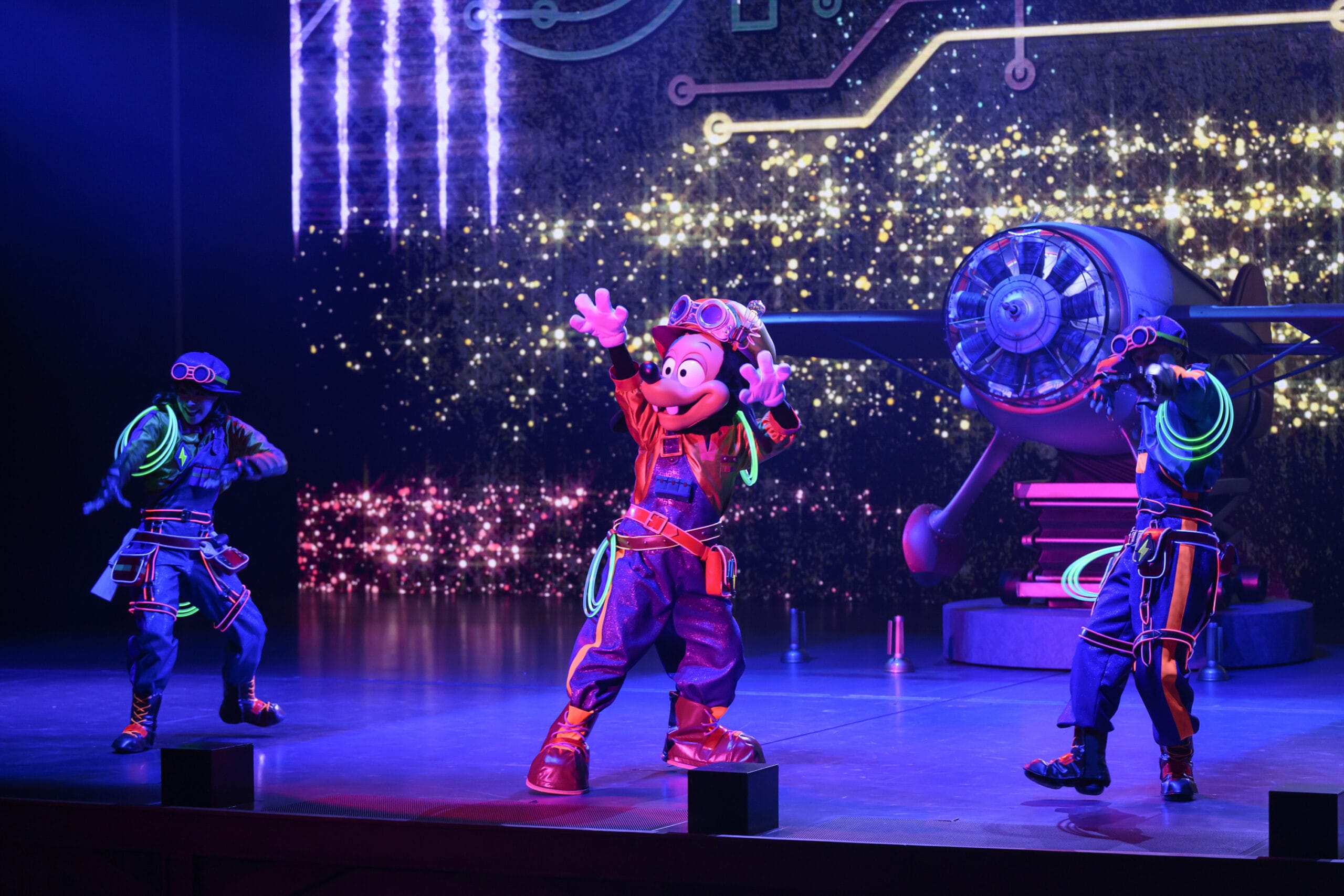 Mickey Mouse and two dancers perform energetically as dreams take flight on a futuristic, colorful Tokyo DisneySea stage.
