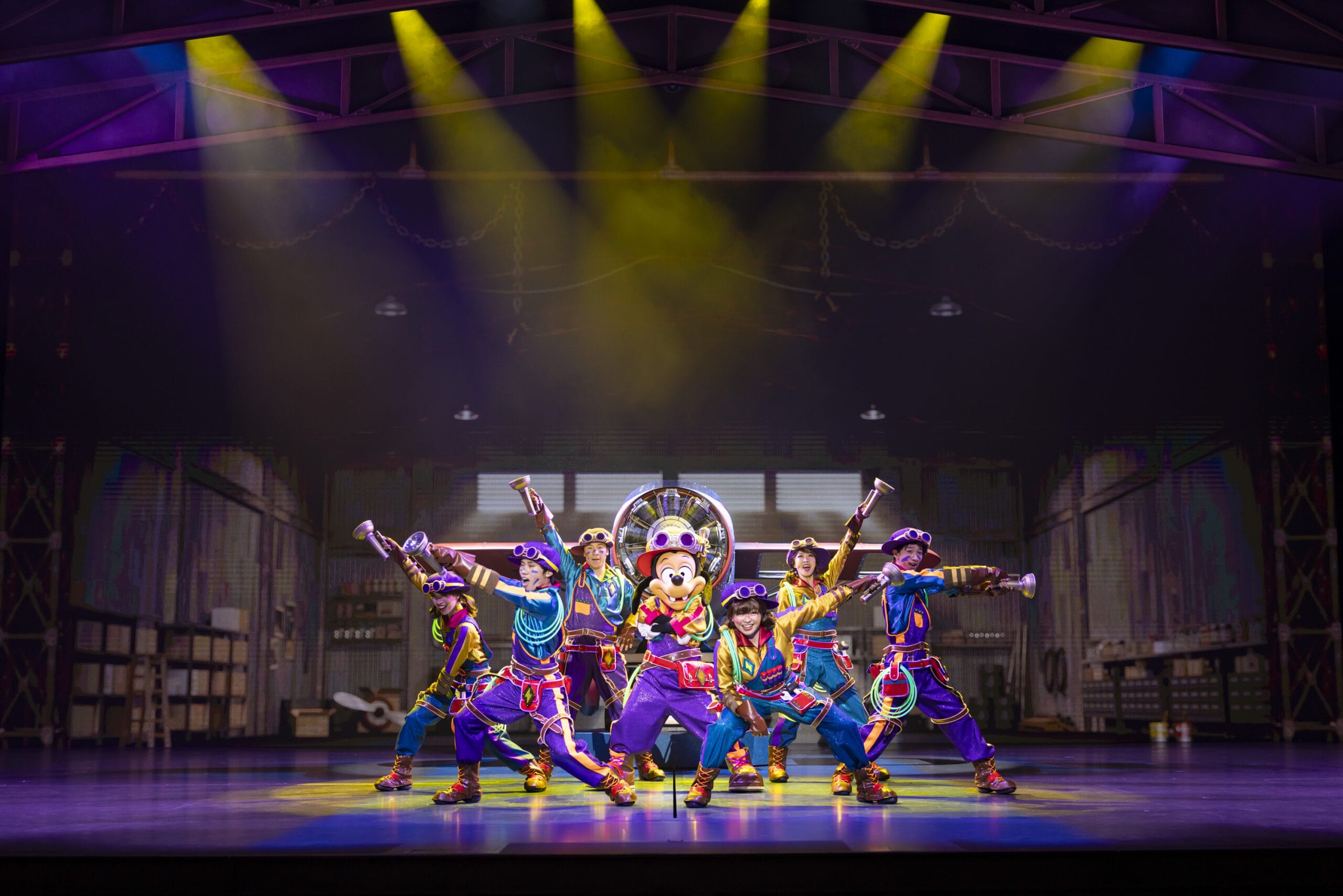 Performers in colorful costumes pose energetically on stage at Tokyo DisneySea as dreams take flight under vibrant lighting.