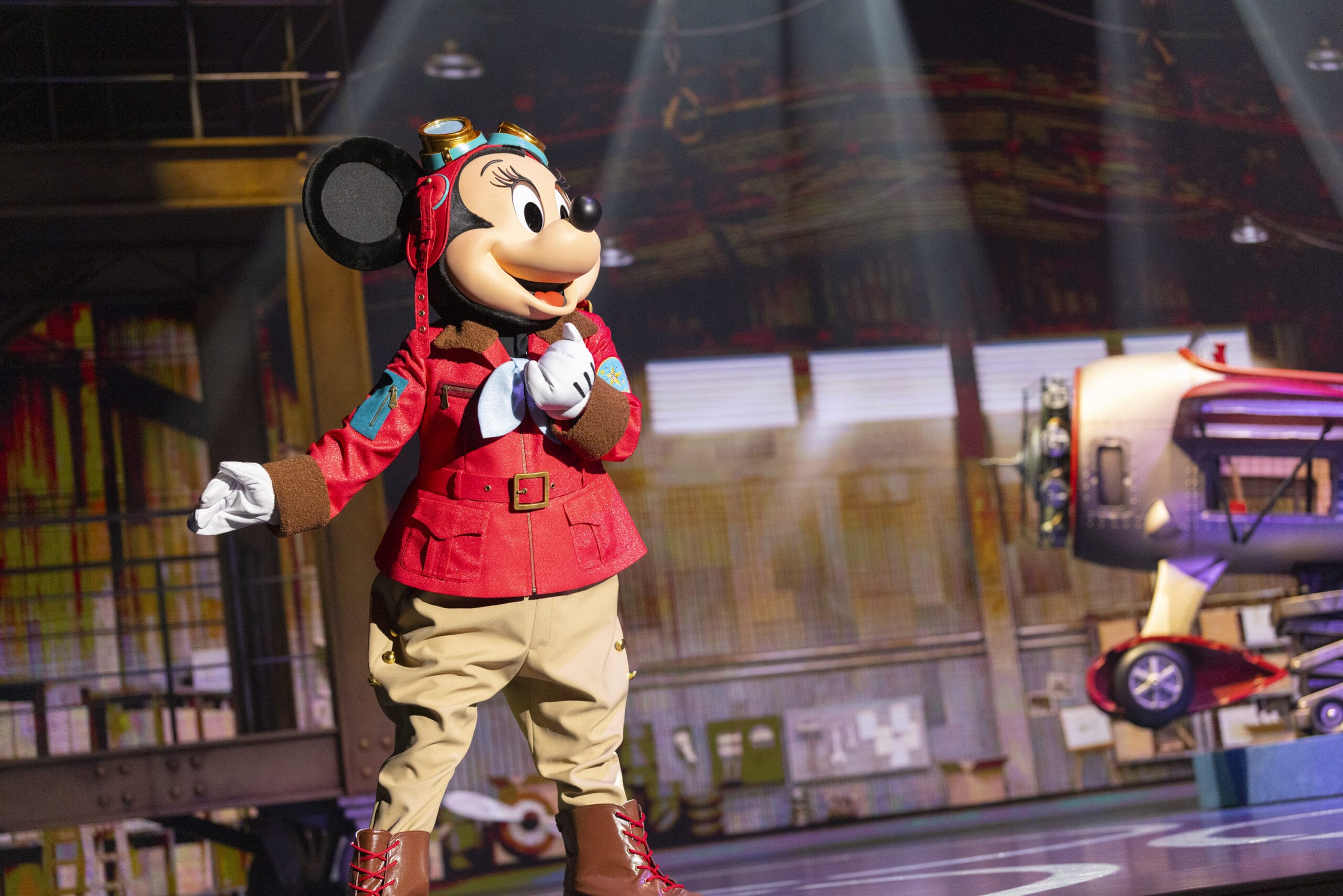 Mickey Mouse in an aviator outfit stands on stage at Tokyo DisneySea as dreams take flight under bright lights.