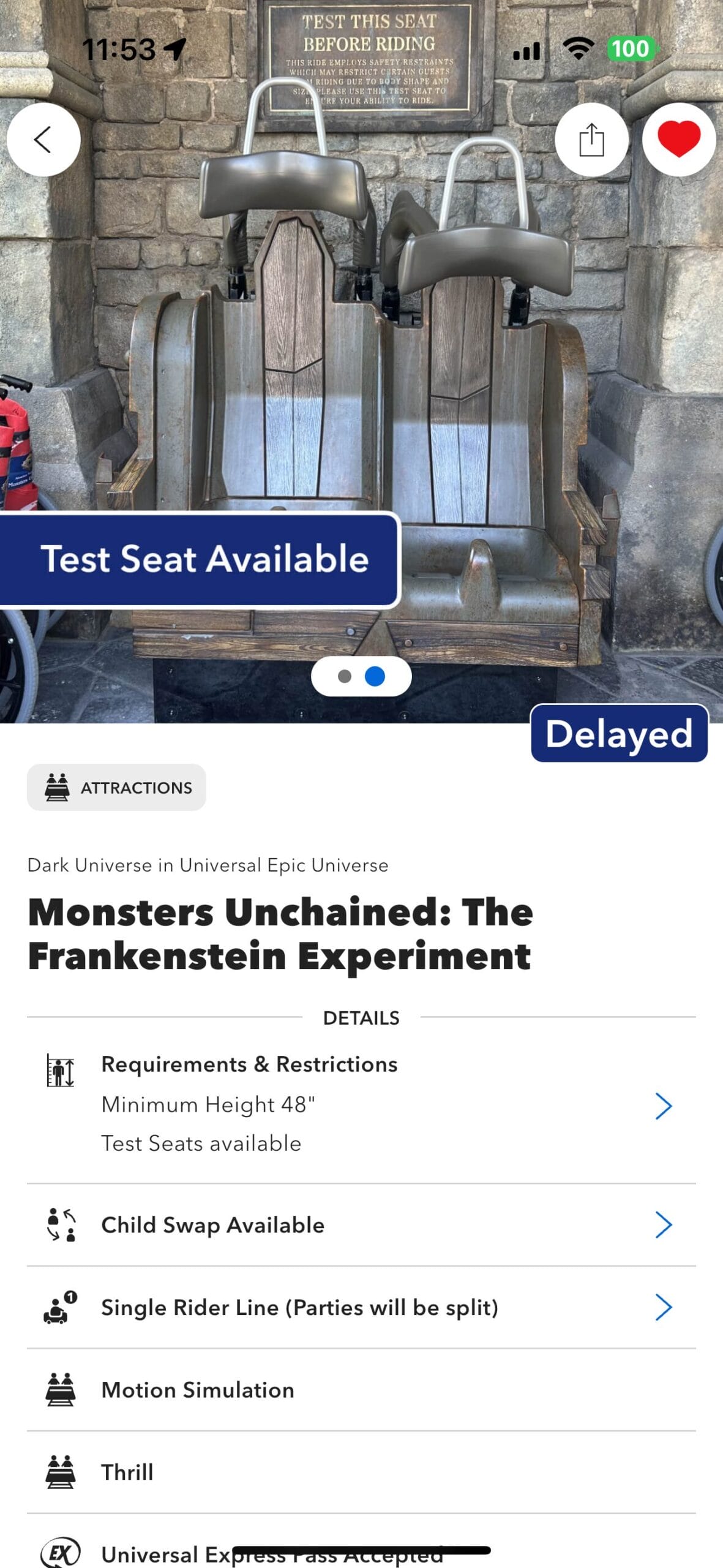 Two empty theme park ride test seats with signs reading "Test Seat Available" and "Delayed" in front of a stone wall.