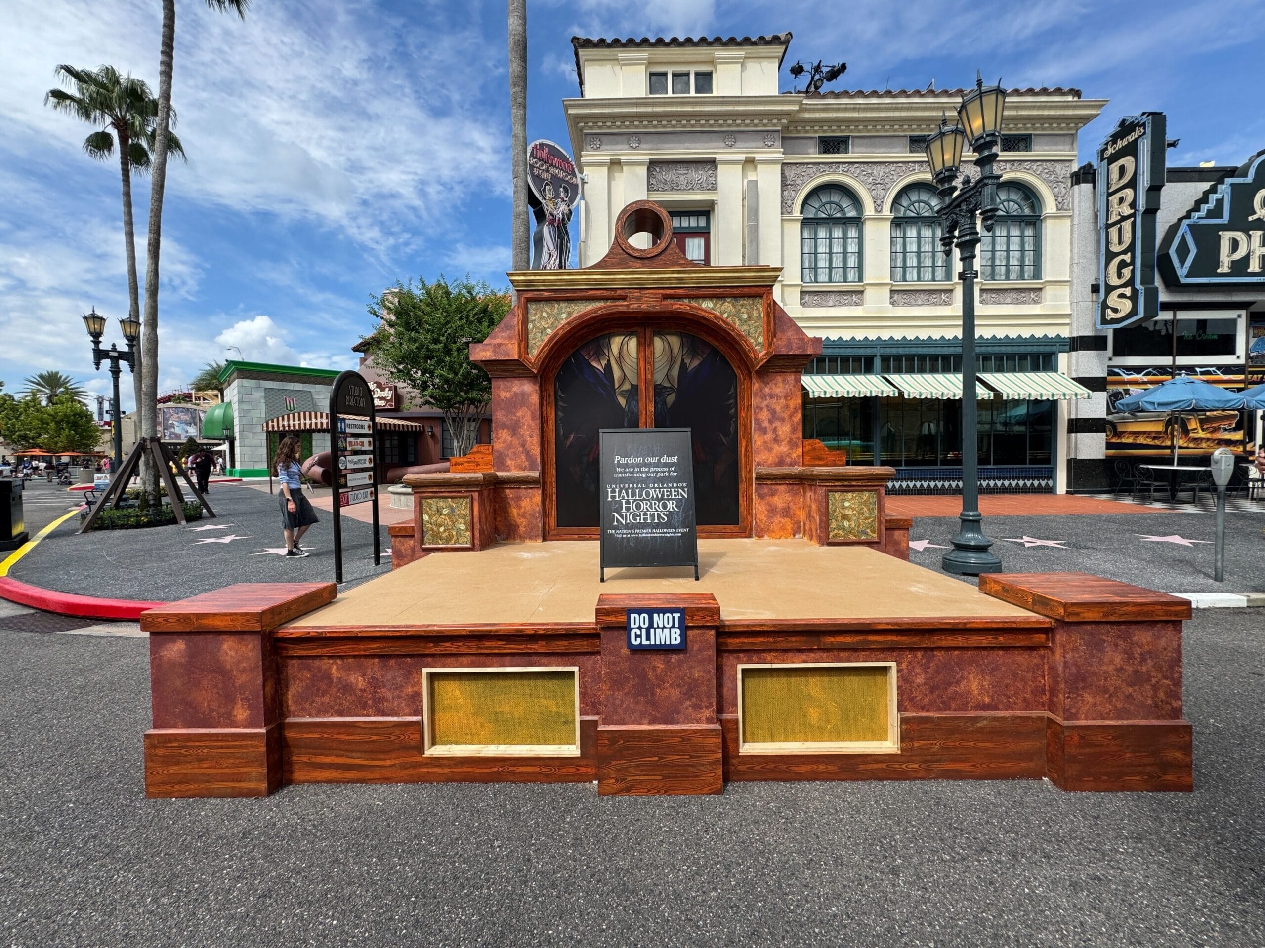 A brown stage with a "Do Not Climb" sign stands outdoors in a Scare Zone at Universal Studios Florida.