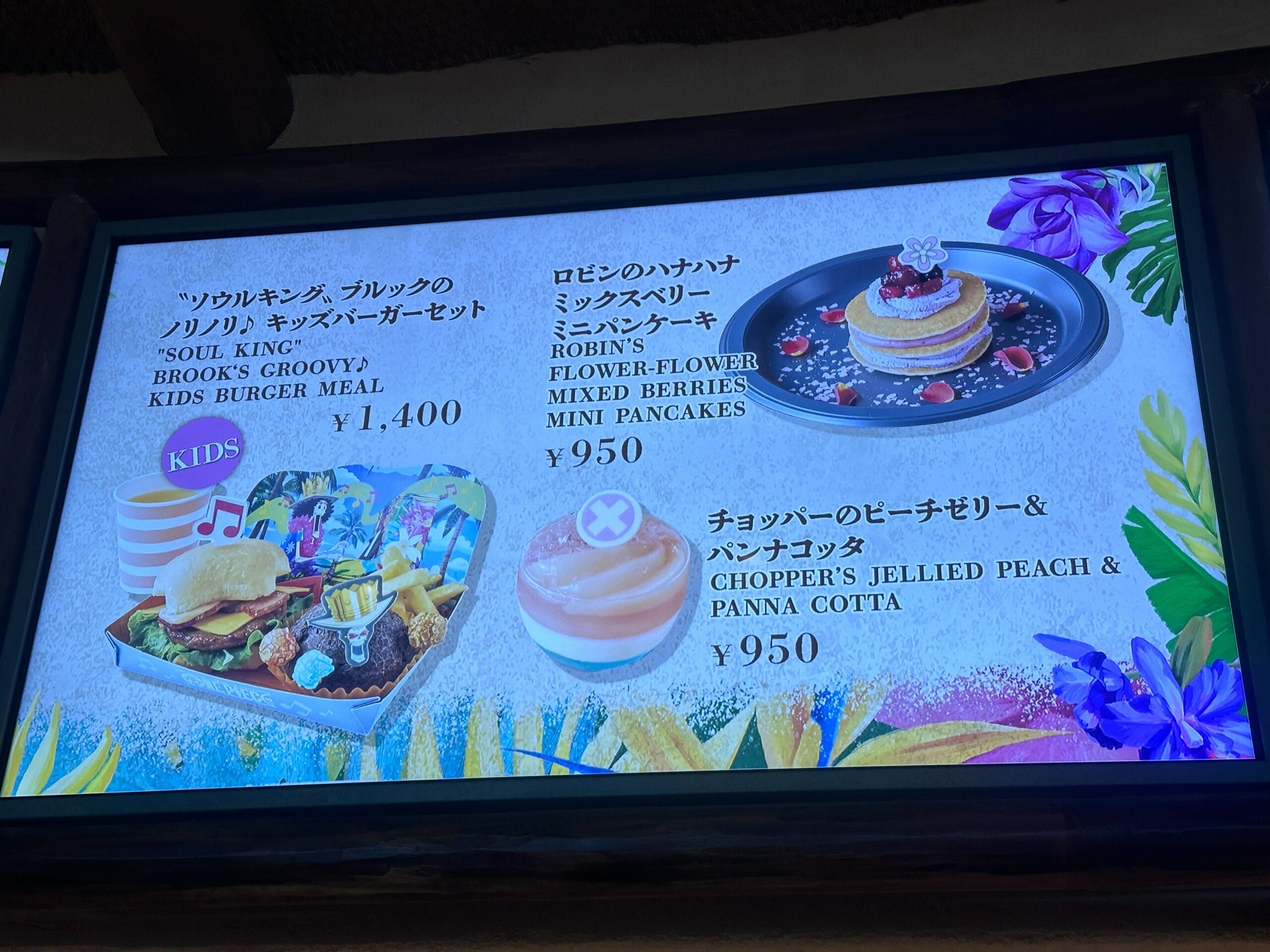Menu display showing a kids burger meal, pancakes with berries, and jellied peach & panna cotta desserts with prices.