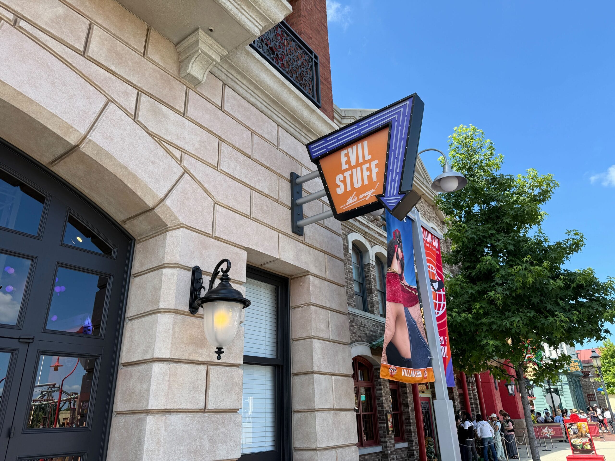 Storefront with a sign reading "Evil Stuff" beneath a blue sky, next to a building and a streetlamp.