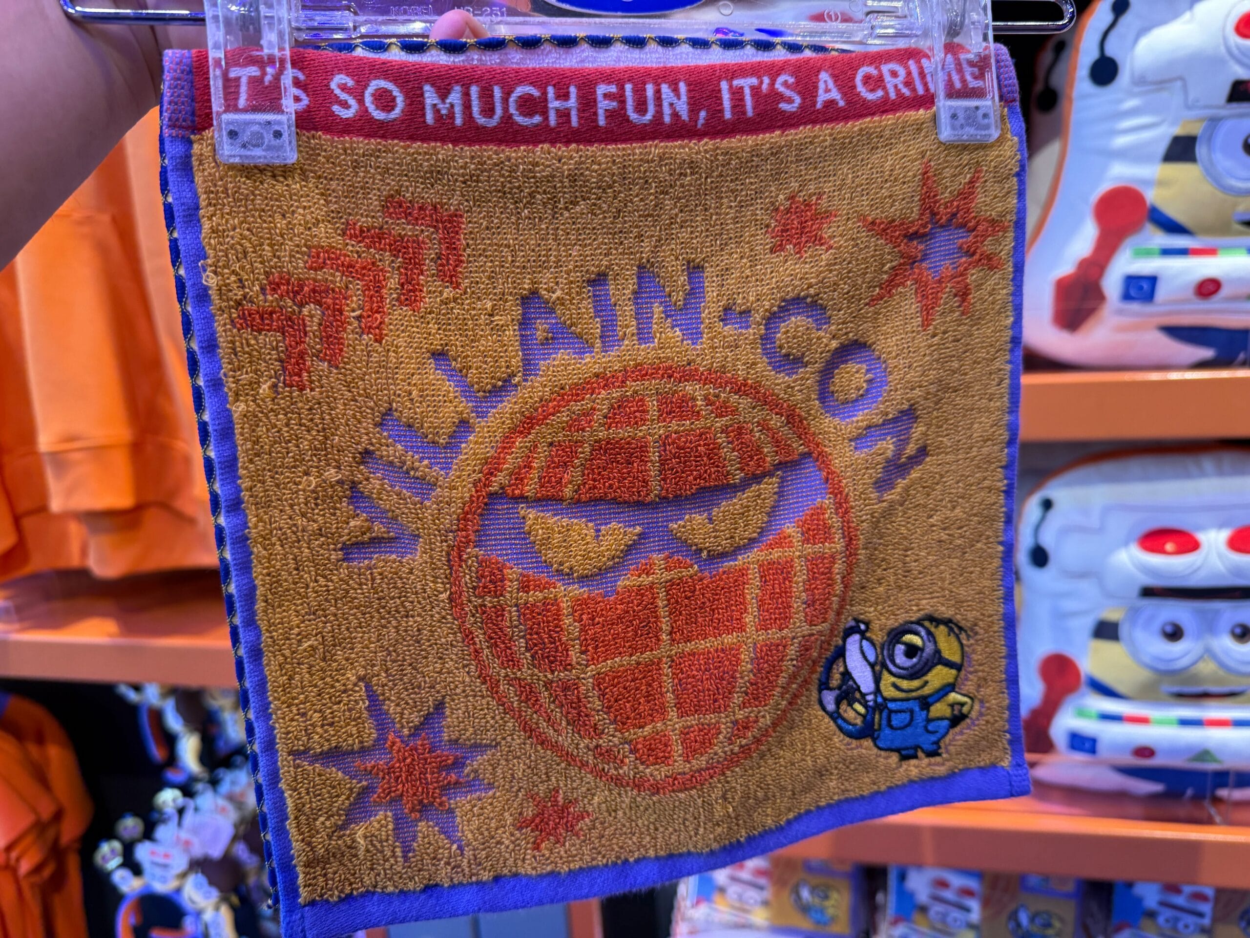 Square cloth with "VILLAIN-CON" and an angry globe face, plus a small Minion holding a device on the lower right.