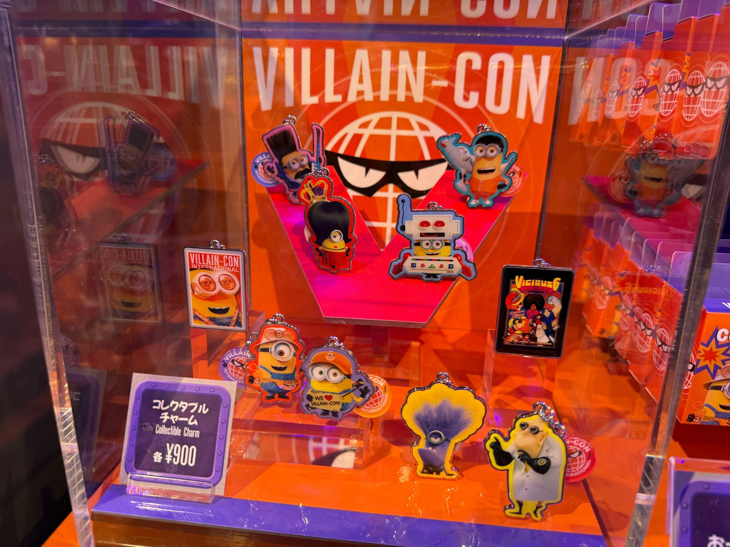 Villain Con-themed Minions keychains and pins displayed in a clear case with a purple and orange background.