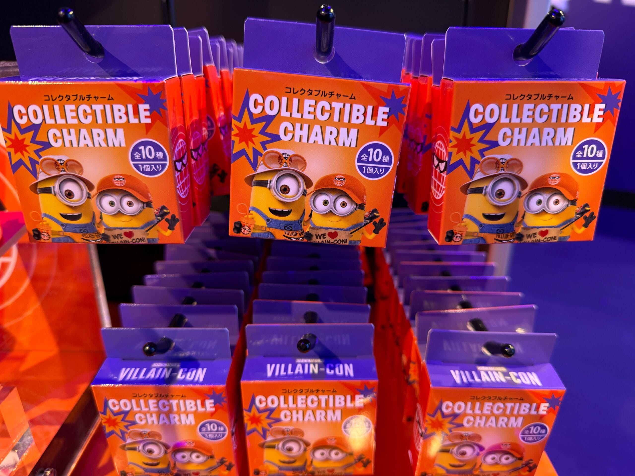 Rows of orange “Collectible Charm” Minions packs are displayed on hooks against a purple background.