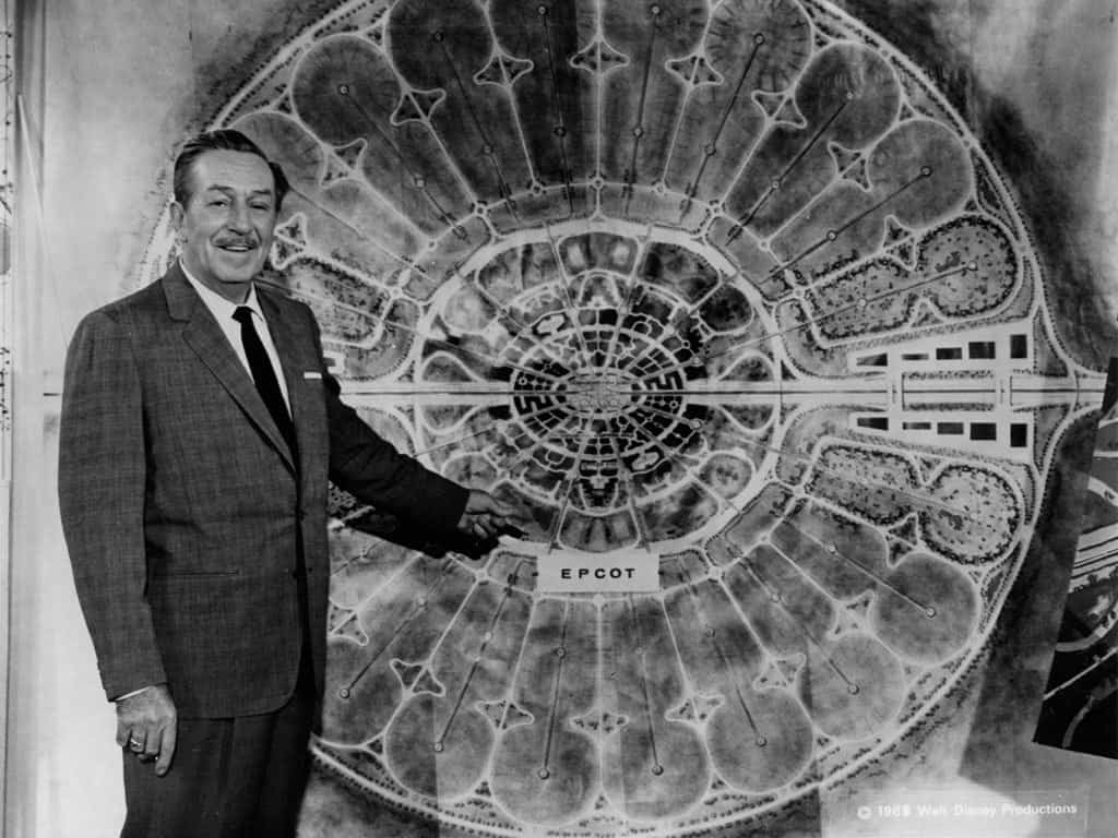 Walt Disney points to a circular EPCOT diagram, smiling—capturing a moment in Walt Disney World history.