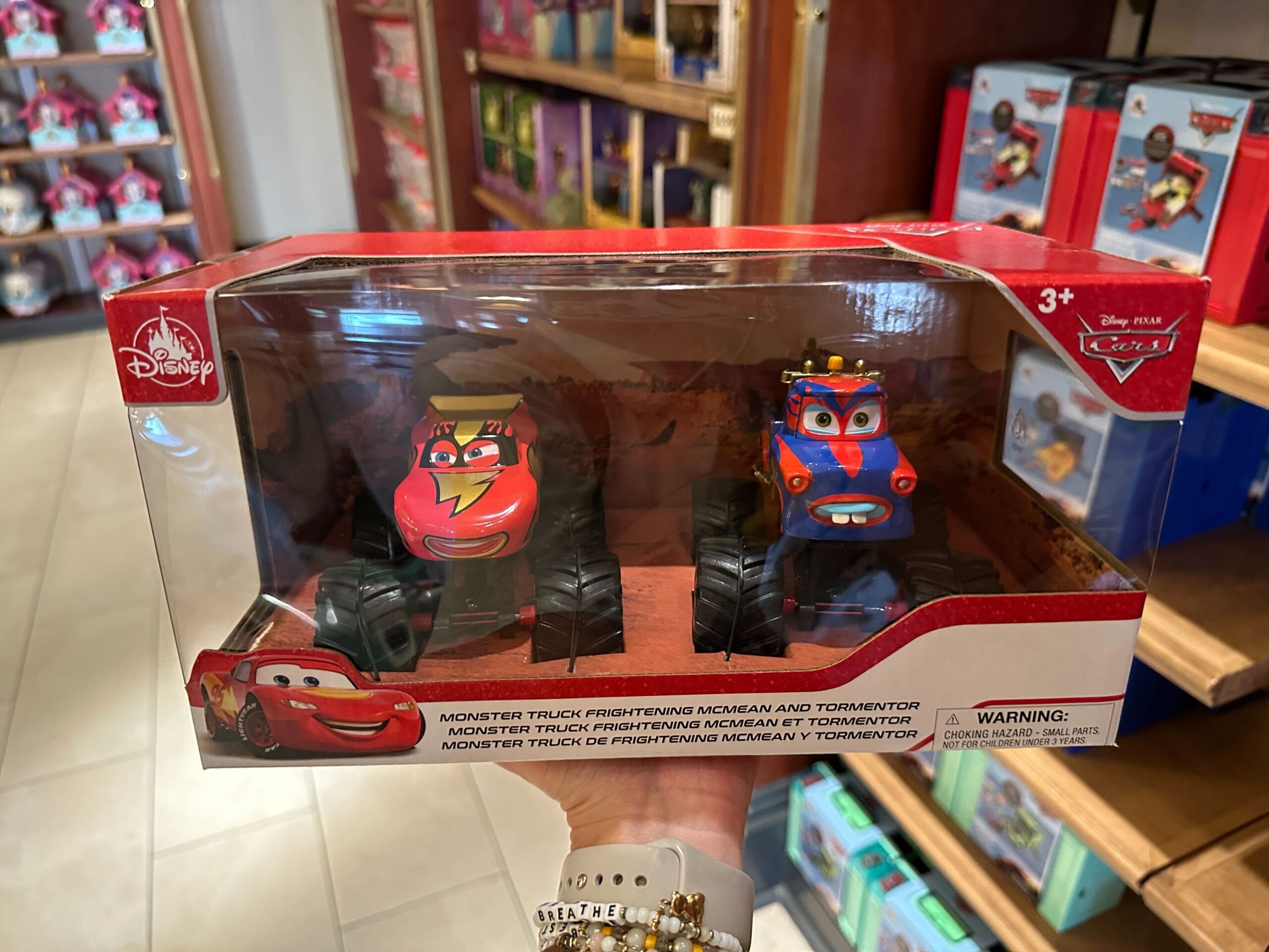 Two Disney Cars monster truck toys, Frightening McMean and Tormentor, in a red display box on a store shelf.
