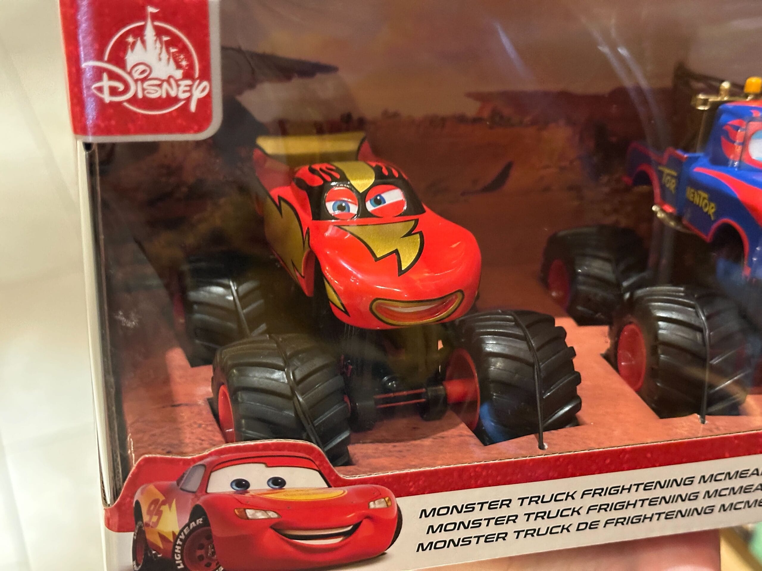 A toy Lightning McQueen monster truck in its Disney packaging with a smiling face on the label.