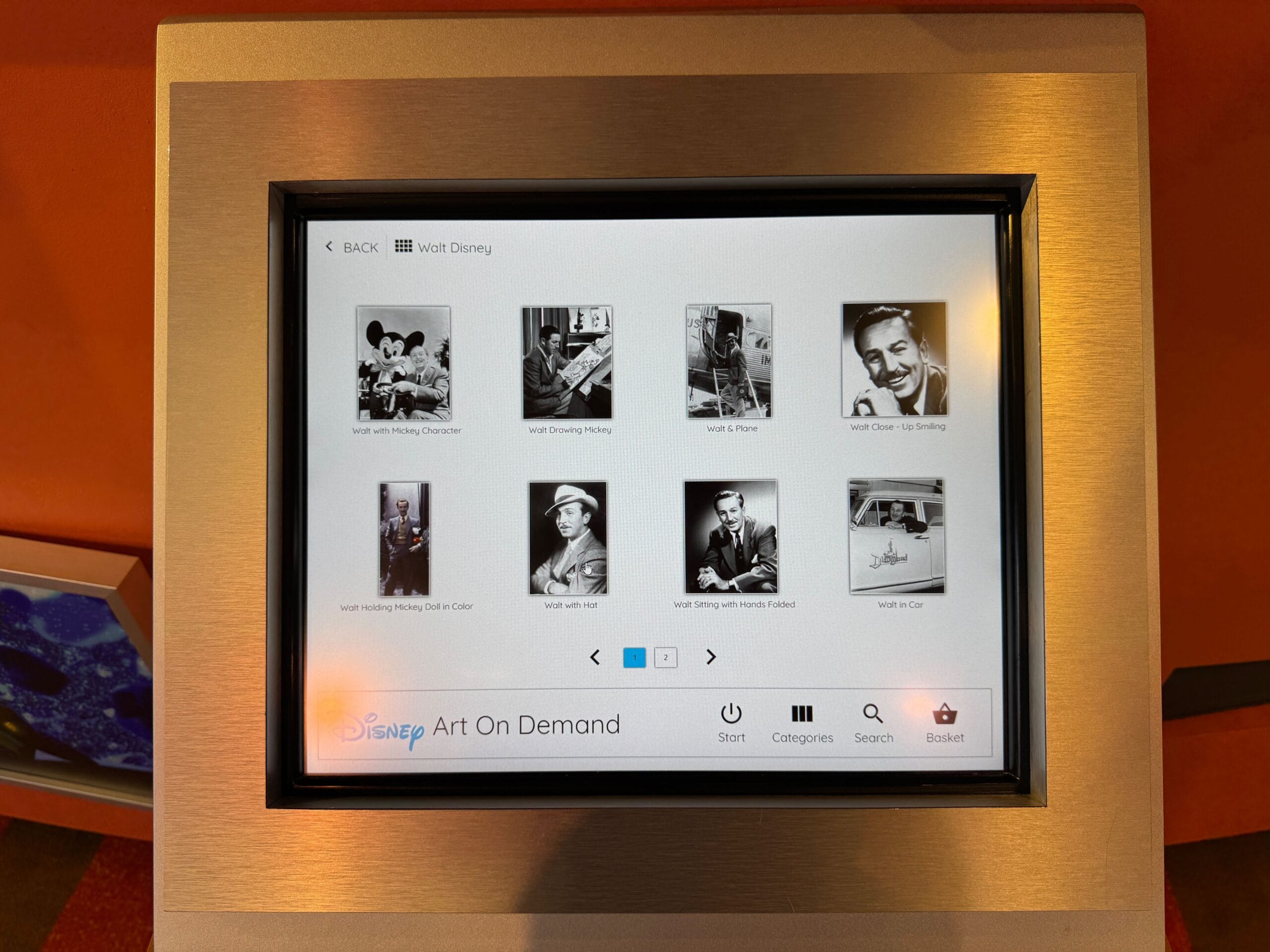 Touchscreen display showing black-and-white photos of Walt Disney and related figures under a "Disney Art On Demand" menu.
