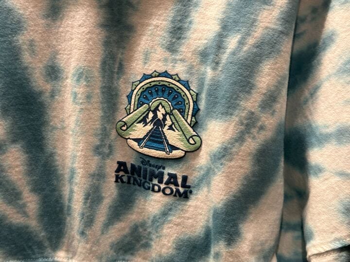Blue tie-dye shirt with a Disney’s Animal Kingdom logo featuring a mountain and stylized design.