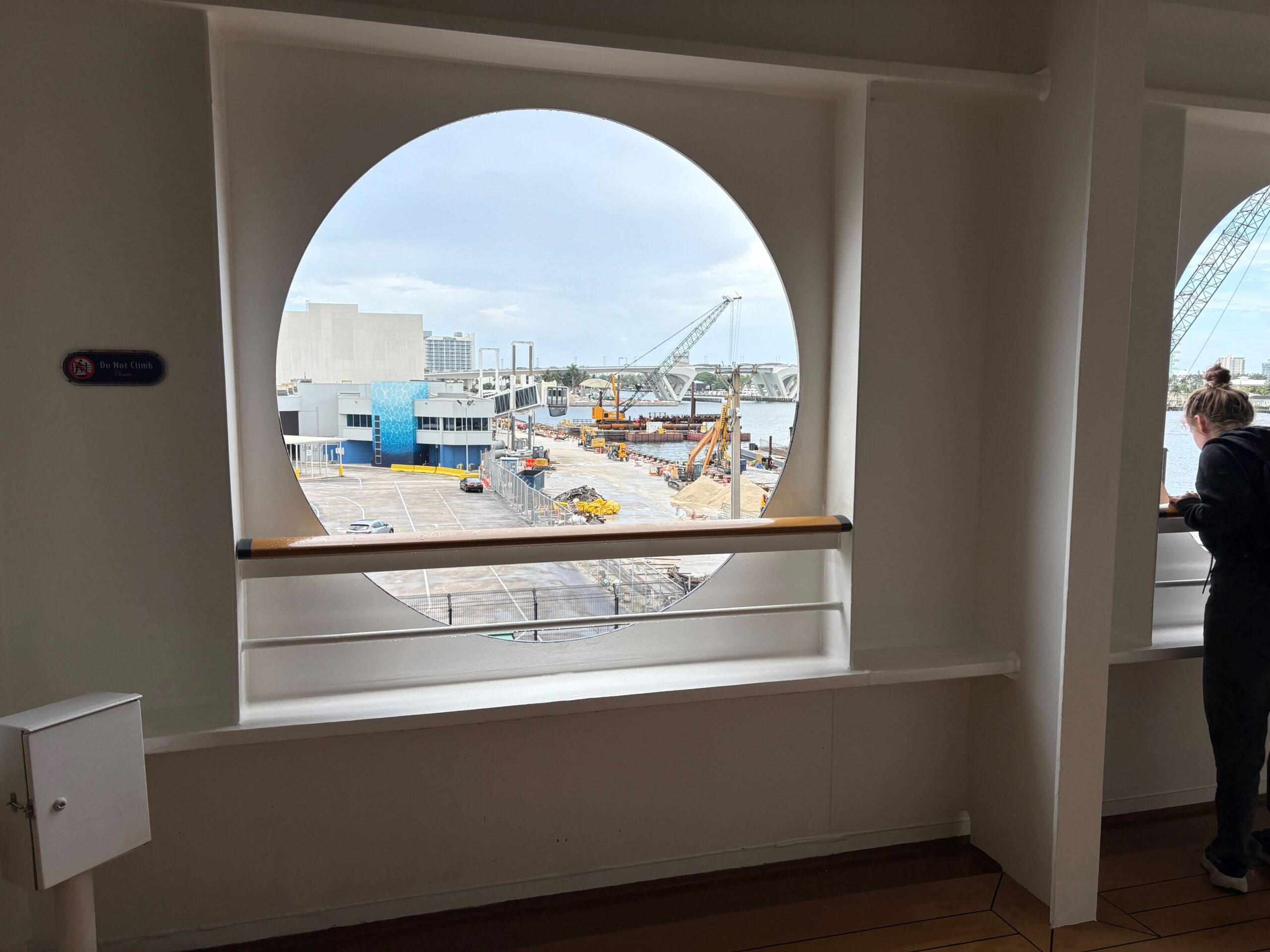 View of a construction site through a Disney Dream porthole, with a person standing to the right.