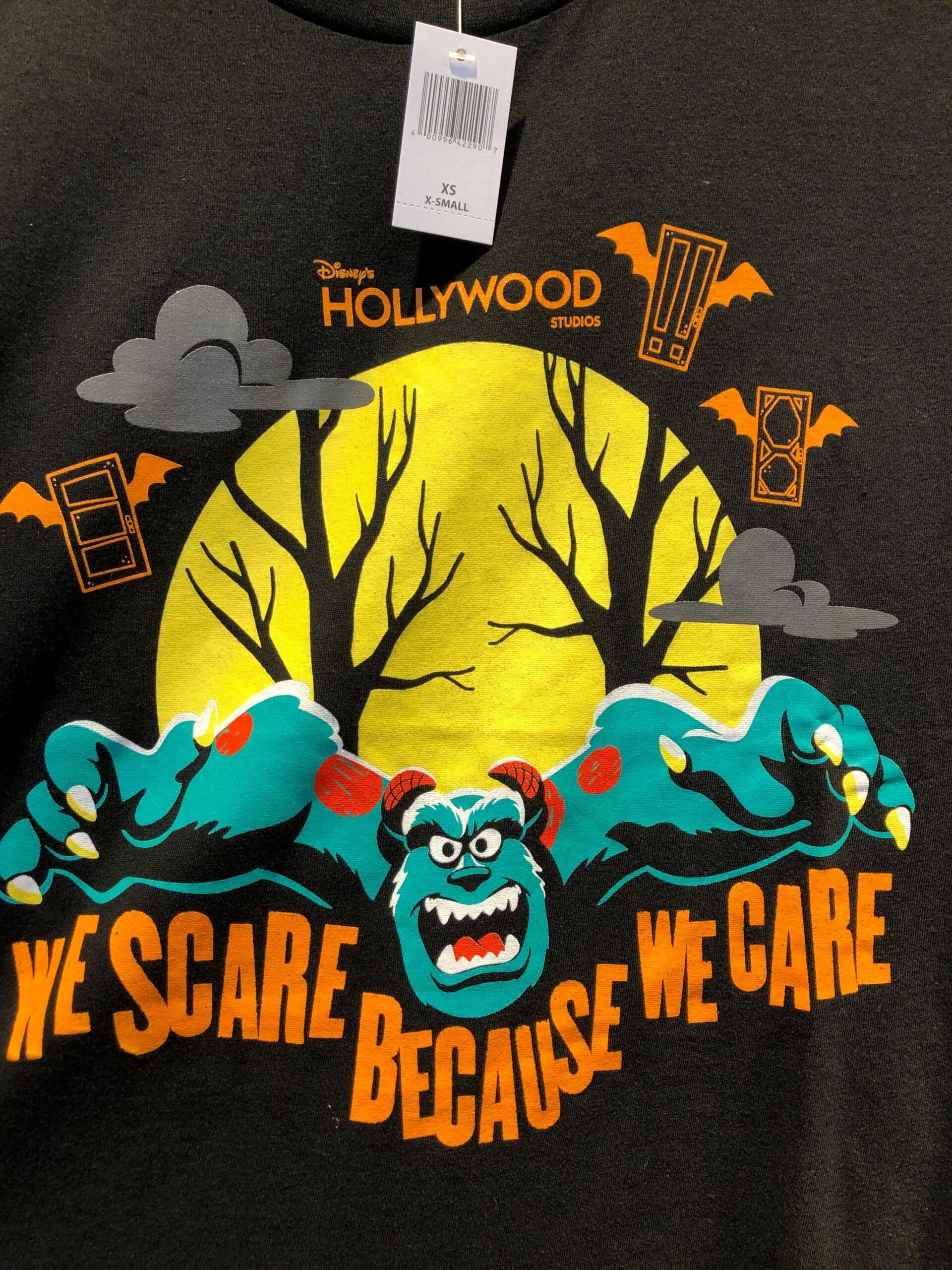 Disney shirt with Monsters, Inc.'s Sulley, a yellow moon, spooky trees, bats, and “We scare because we care” text.