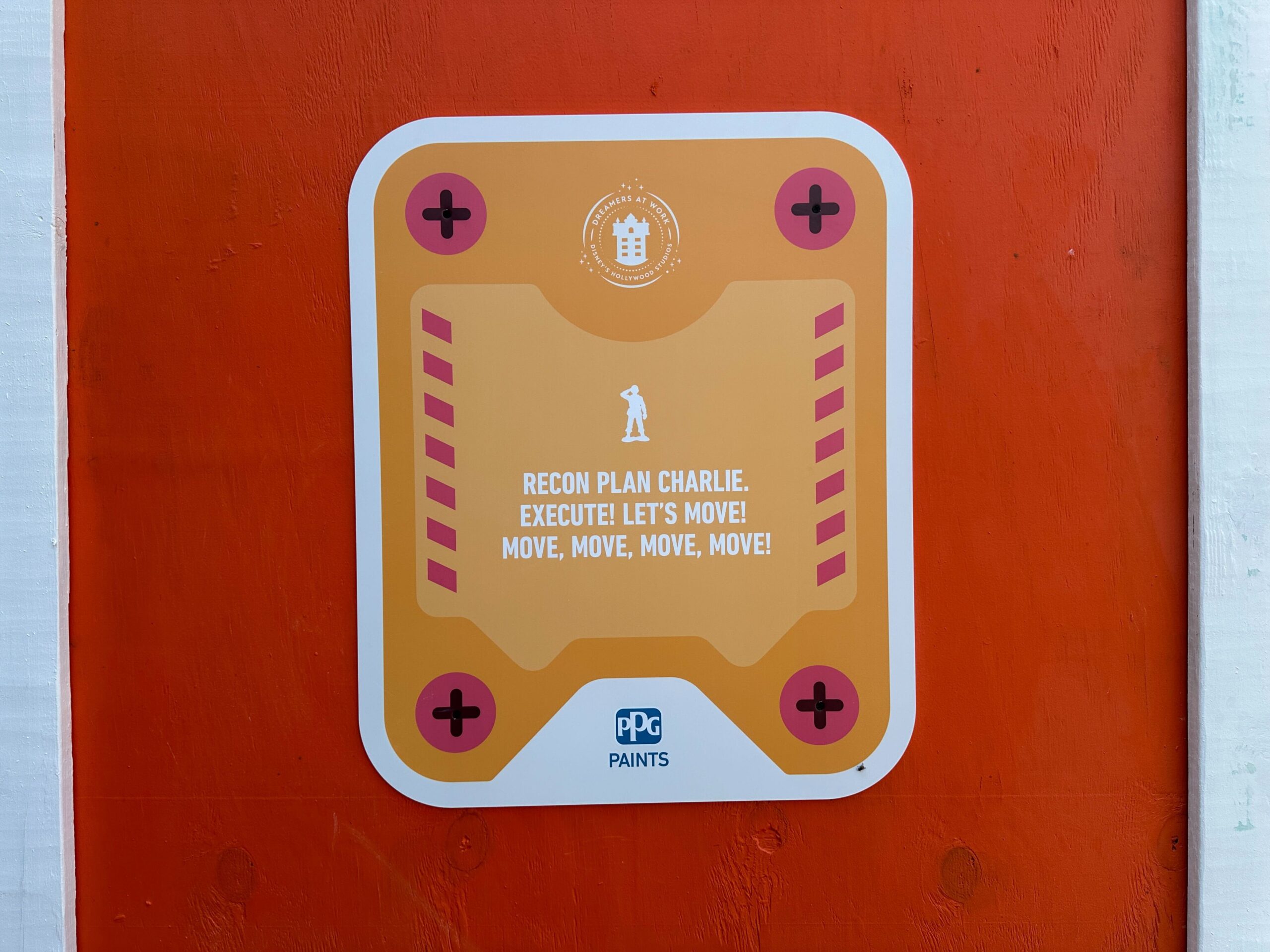 A sign on an orange Toy Story Walls reads: “RECON PLAN CHARLIE. EXECUTE! LET’S MOVE!” with PPG Paints logo.