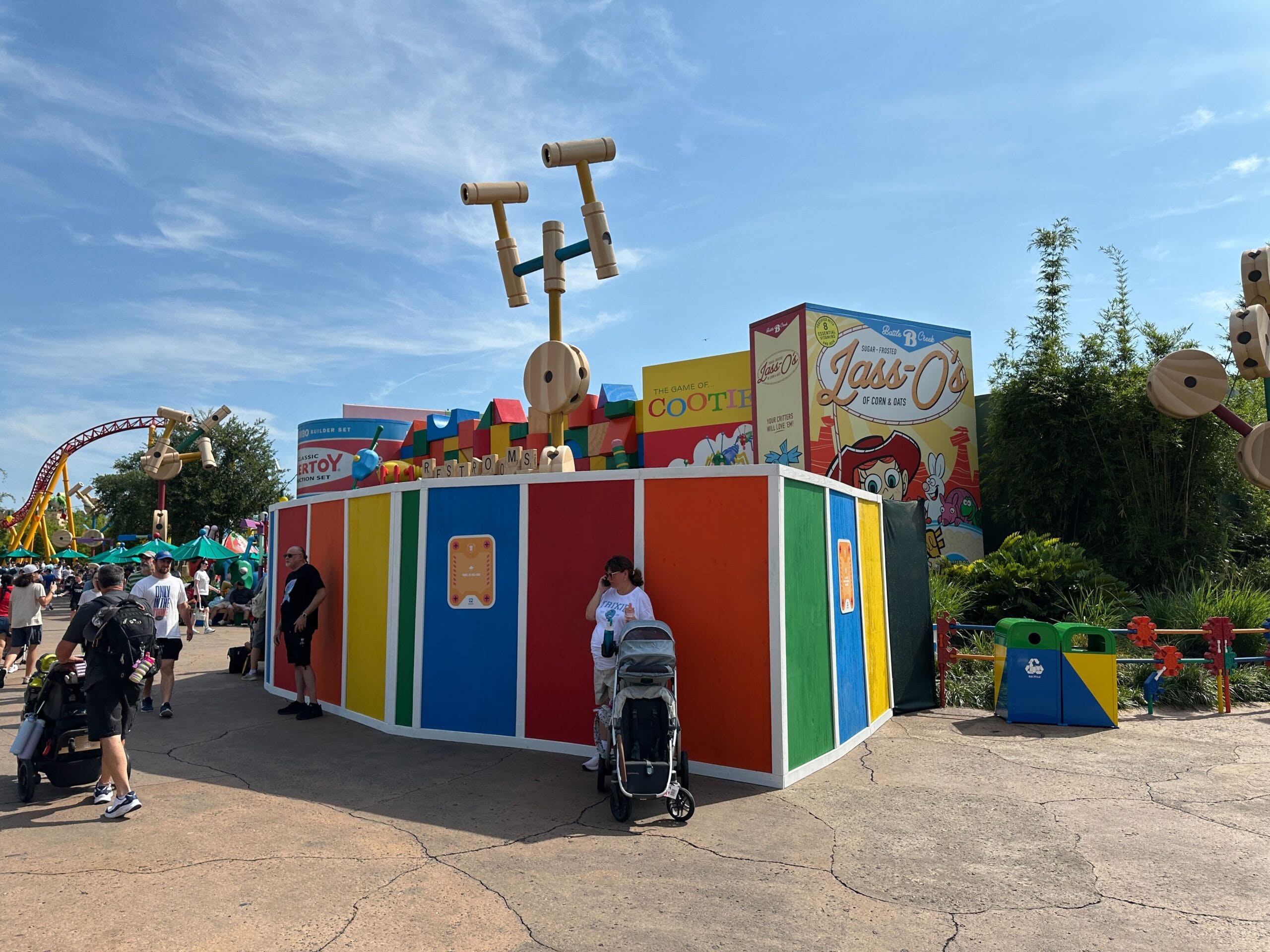 A colorful Toy Story Walls construction wall in Toy Story Land with people walking and a stroller parked in front.