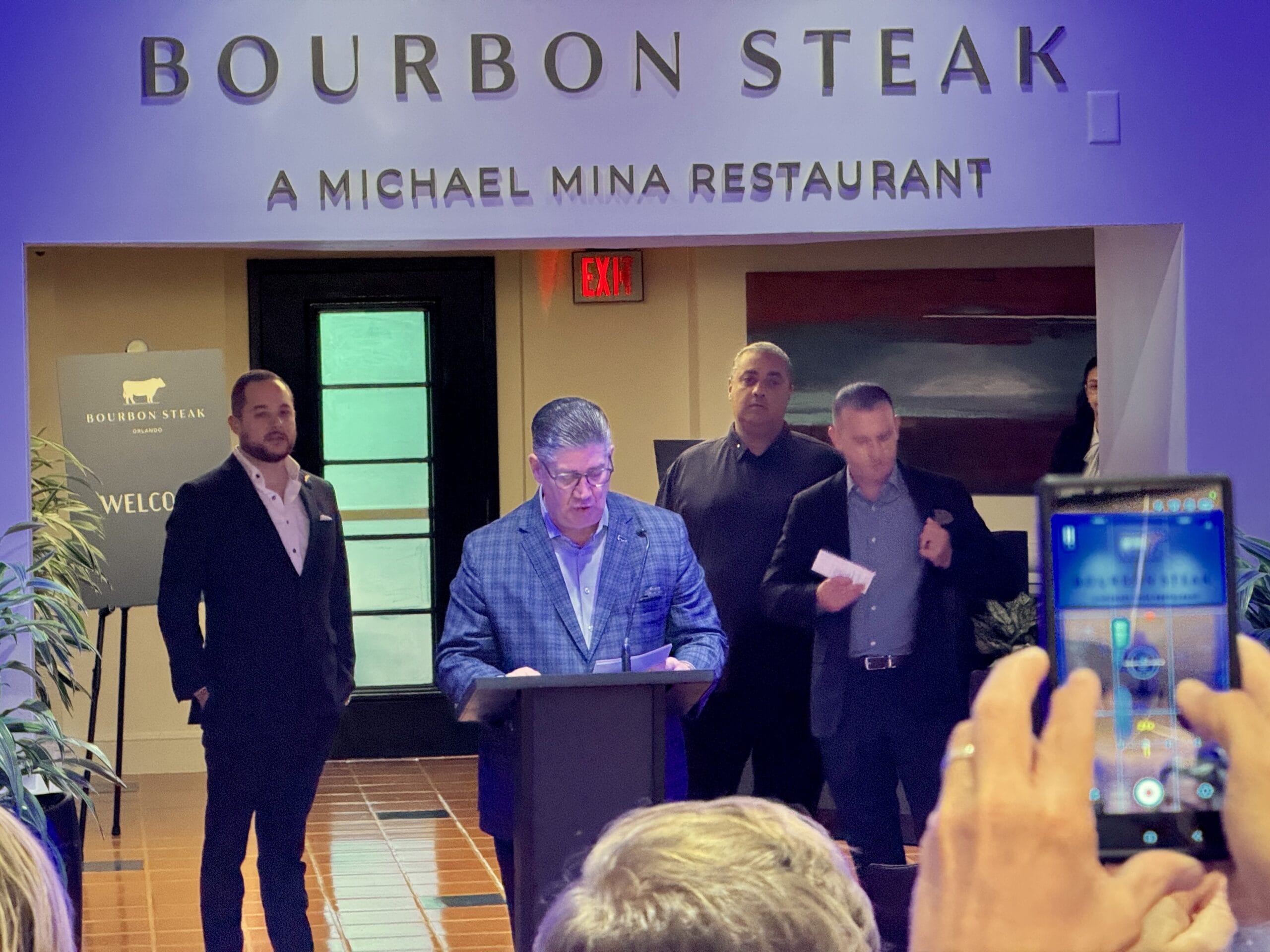 A man speaks at a podium in Bourbon Steak, Michael Mina’s restaurant at the Walt Disney World Dolphin Hotel.