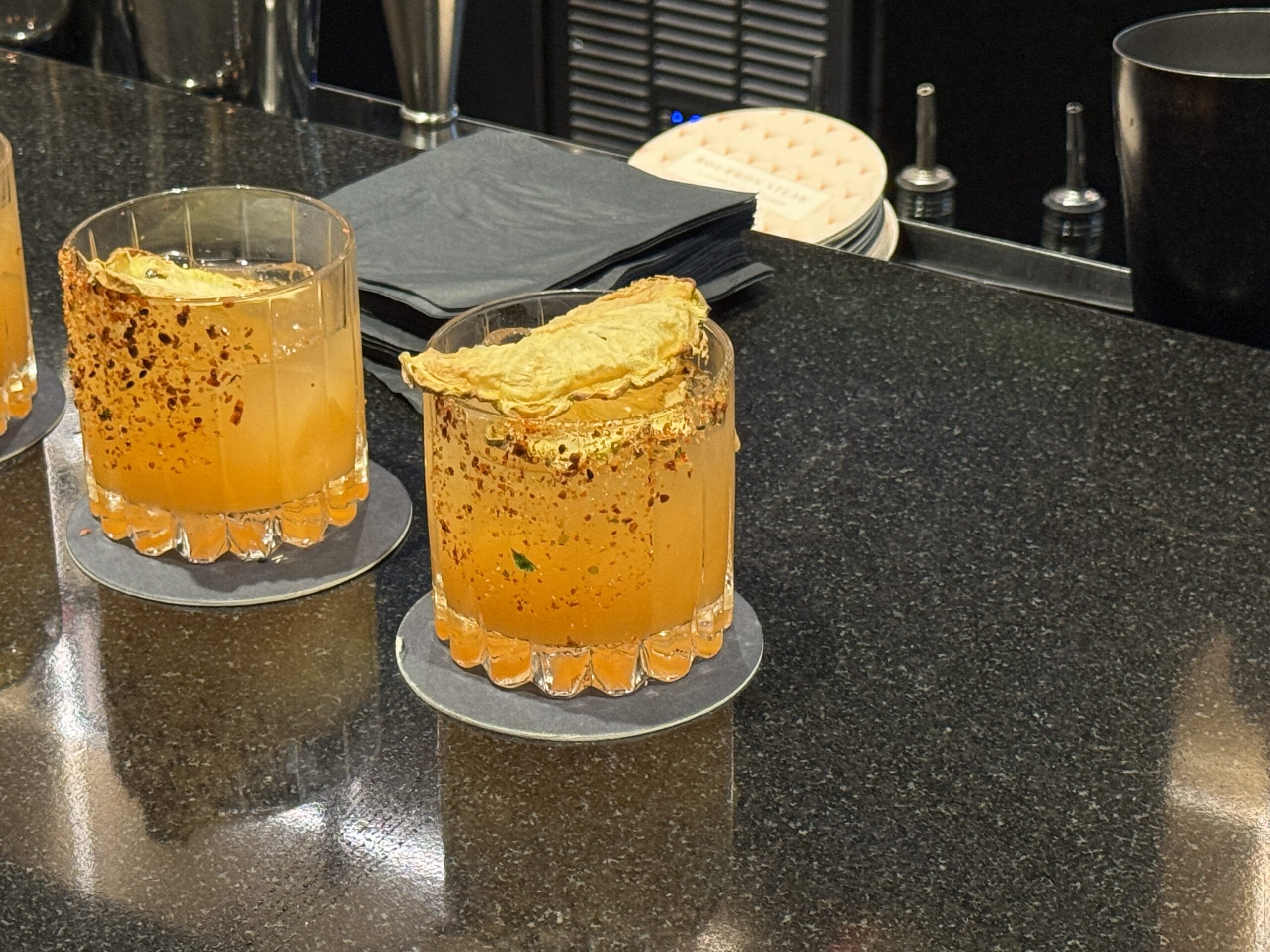 Two orange cocktails at Bourbon Steak, Michael Mina’s spot in Walt Disney World Dolphin Hotel, rimmed with spice and dried fruit.