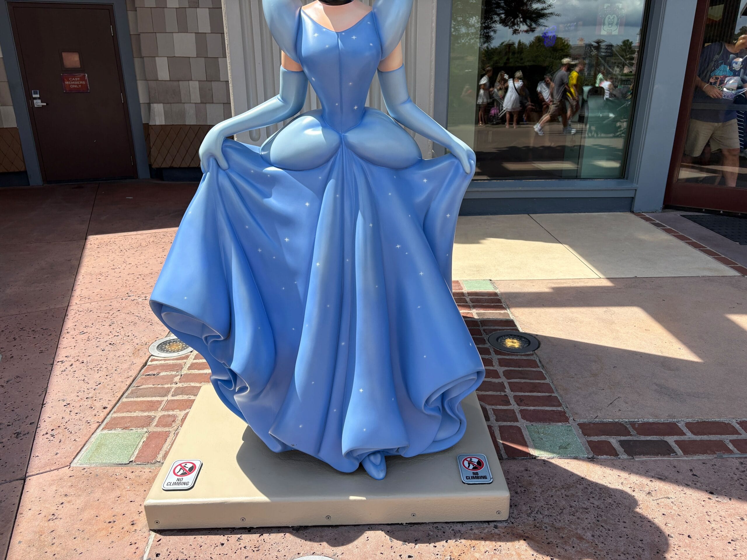 Cinderella Statue in a blue dress at Disney Springs, outdoors with a "do not climb" sign on the base.