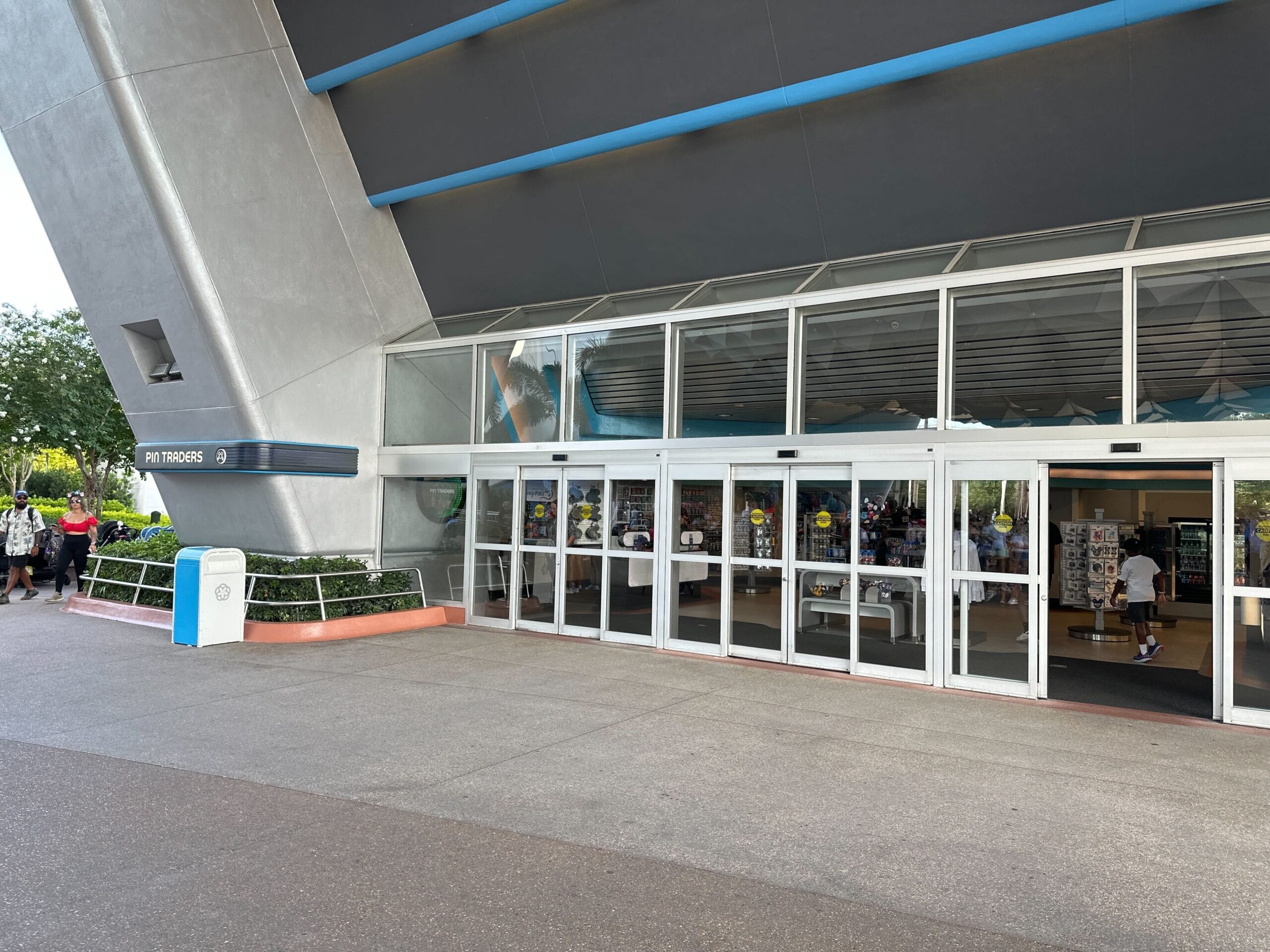 Automatic sliding glass doors at a modern building entrance, with people using MagicBand+ visible inside and outside.