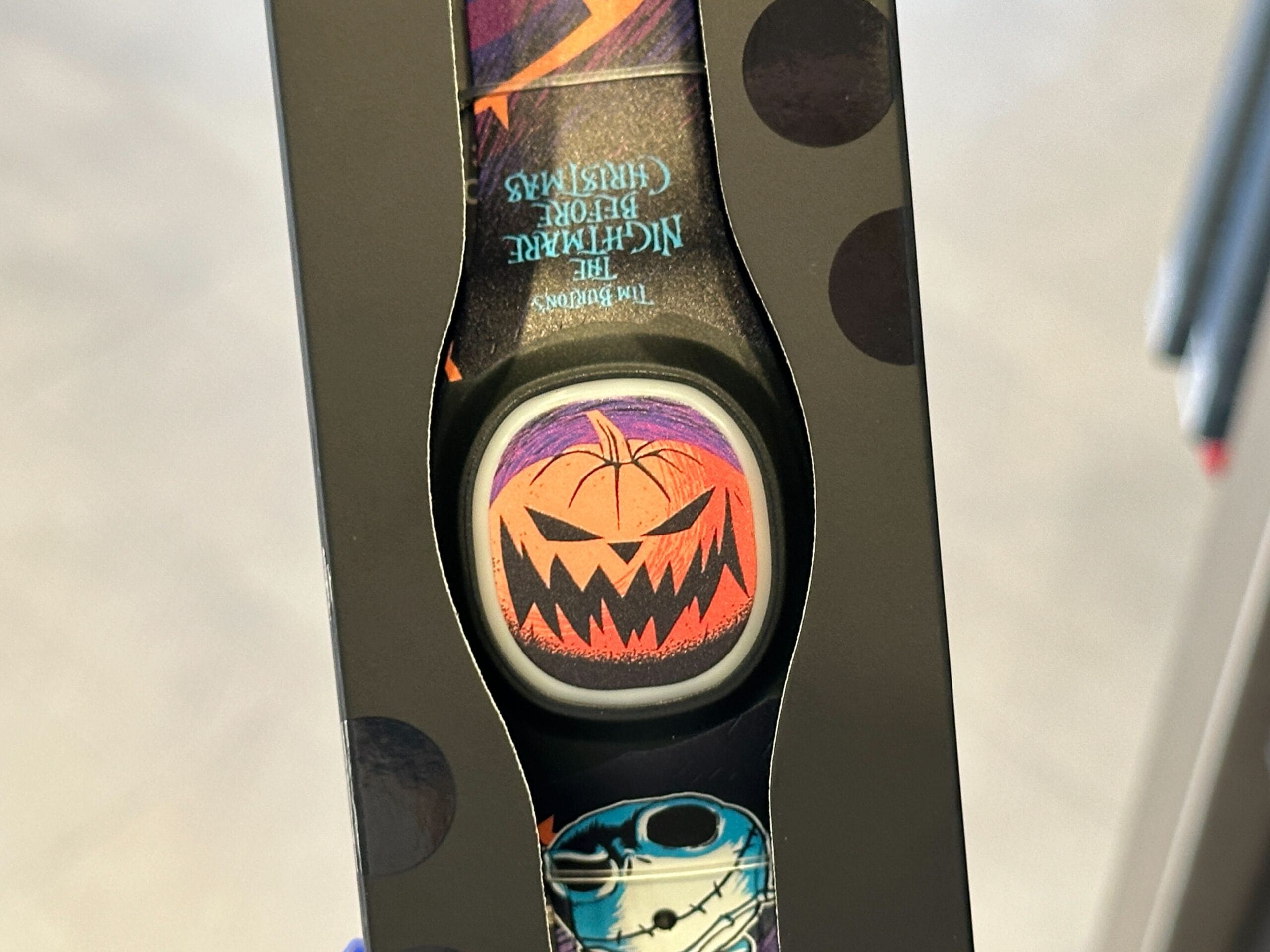 Close-up of a MagicBand+ with a grinning orange jack-o'-lantern and other Halloween-themed designs.
