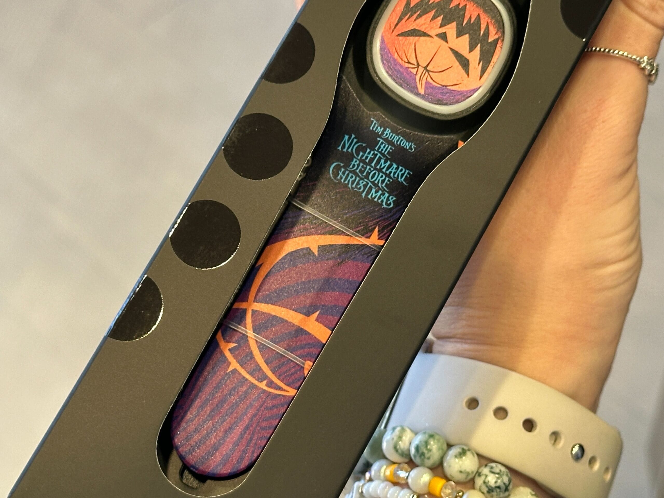 A hand holds a box containing Nightmare Before Christmas themed socks with purple and orange designs at EPCOT.