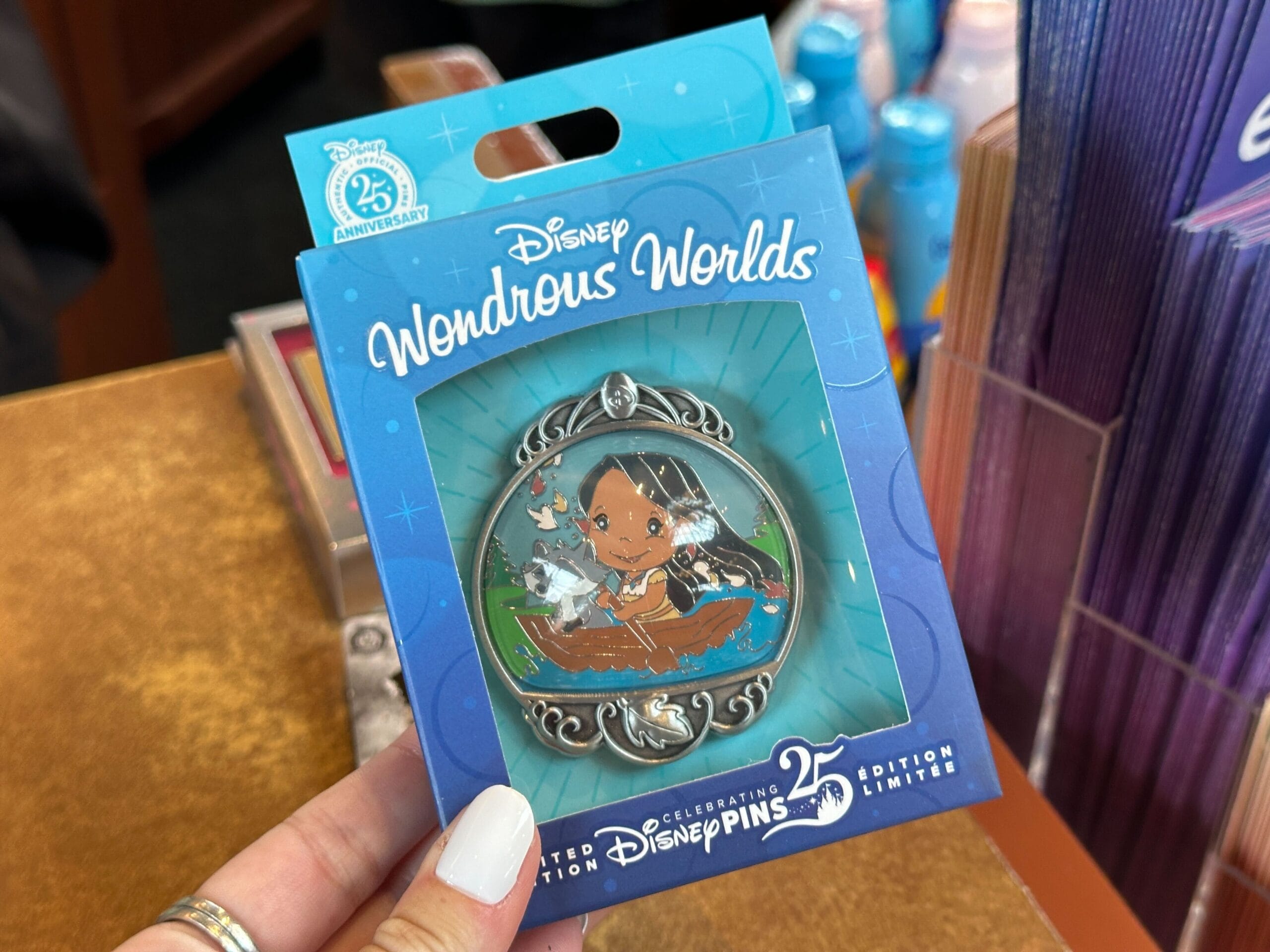 A hand holds a Disney Wondrous Worlds 25th anniversary limited edition Moana collectible pin in packaging.