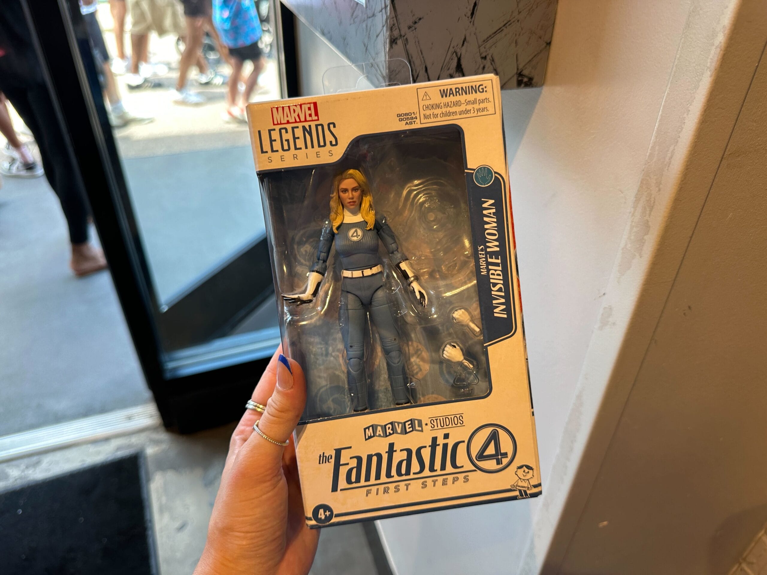 A hand holding a Marvel Legends Invisible Woman action figure, a must-have for any Marvel merchandise collector.