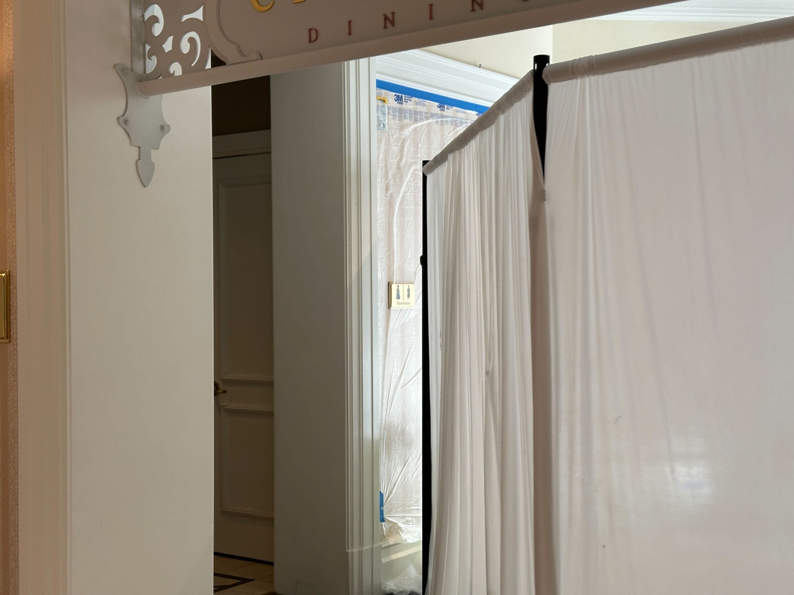 White curtains block off a hallway near a partially visible door and an ornate sign with the word "DINING" above.