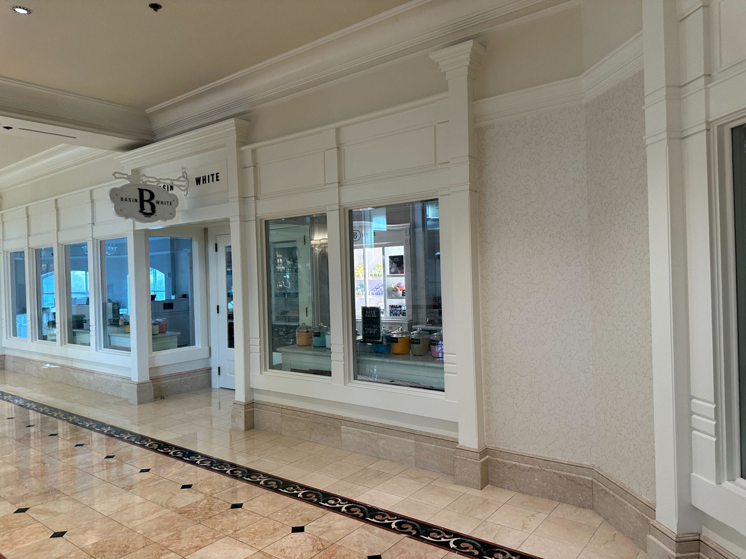 An empty mall hallway with a closed storefront labeled “Baskin-Robbins” and reflective tiled floors.