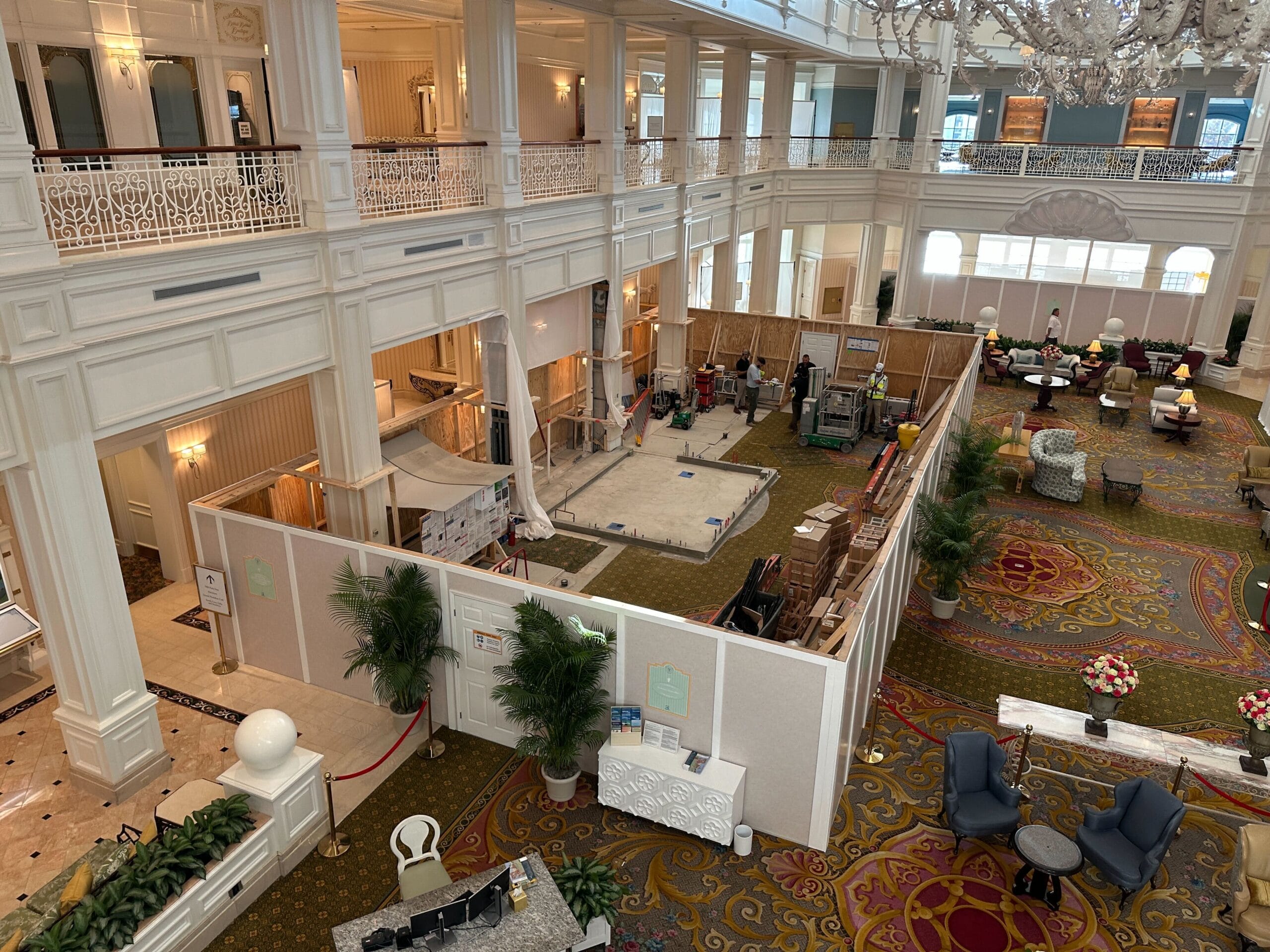 Disney's Grand Floridian lobby under renovation, with construction barriers and workers, surrounded by elegant décor and furniture.