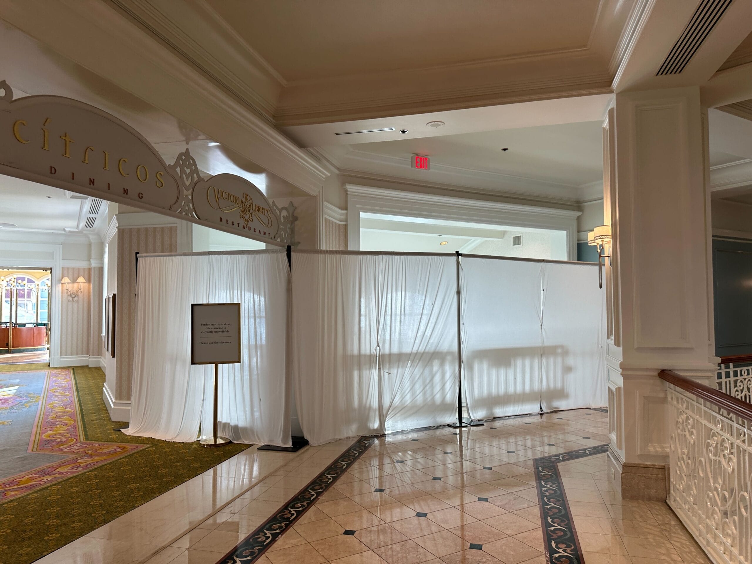 White curtains block off a hallway near restaurant entrances in a hotel, with a sign displayed in front.