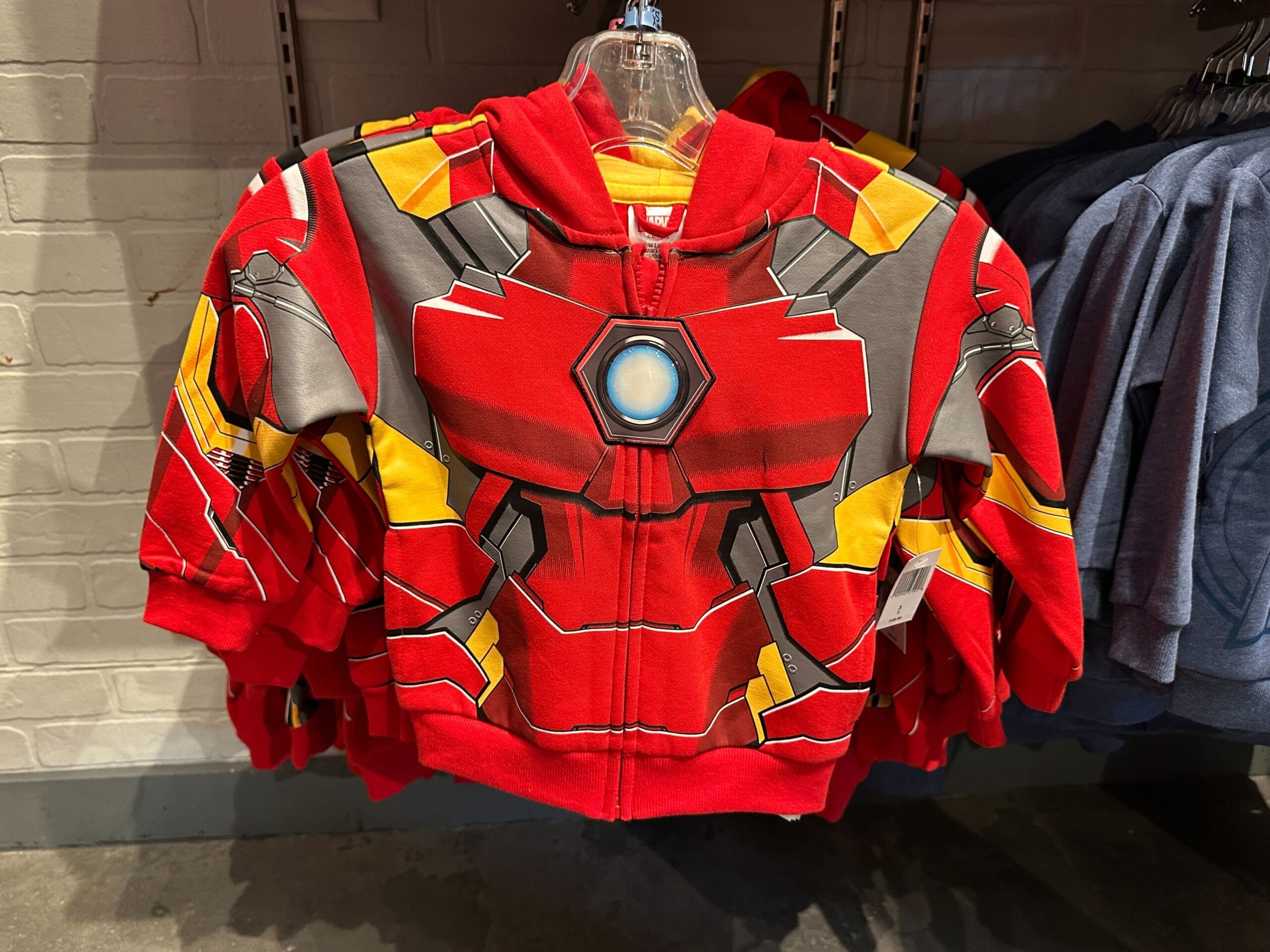 Red and yellow youth Avengers apparel hoodie styled like Iron Man’s suit, hanging on a store rack at Walt Disney World.