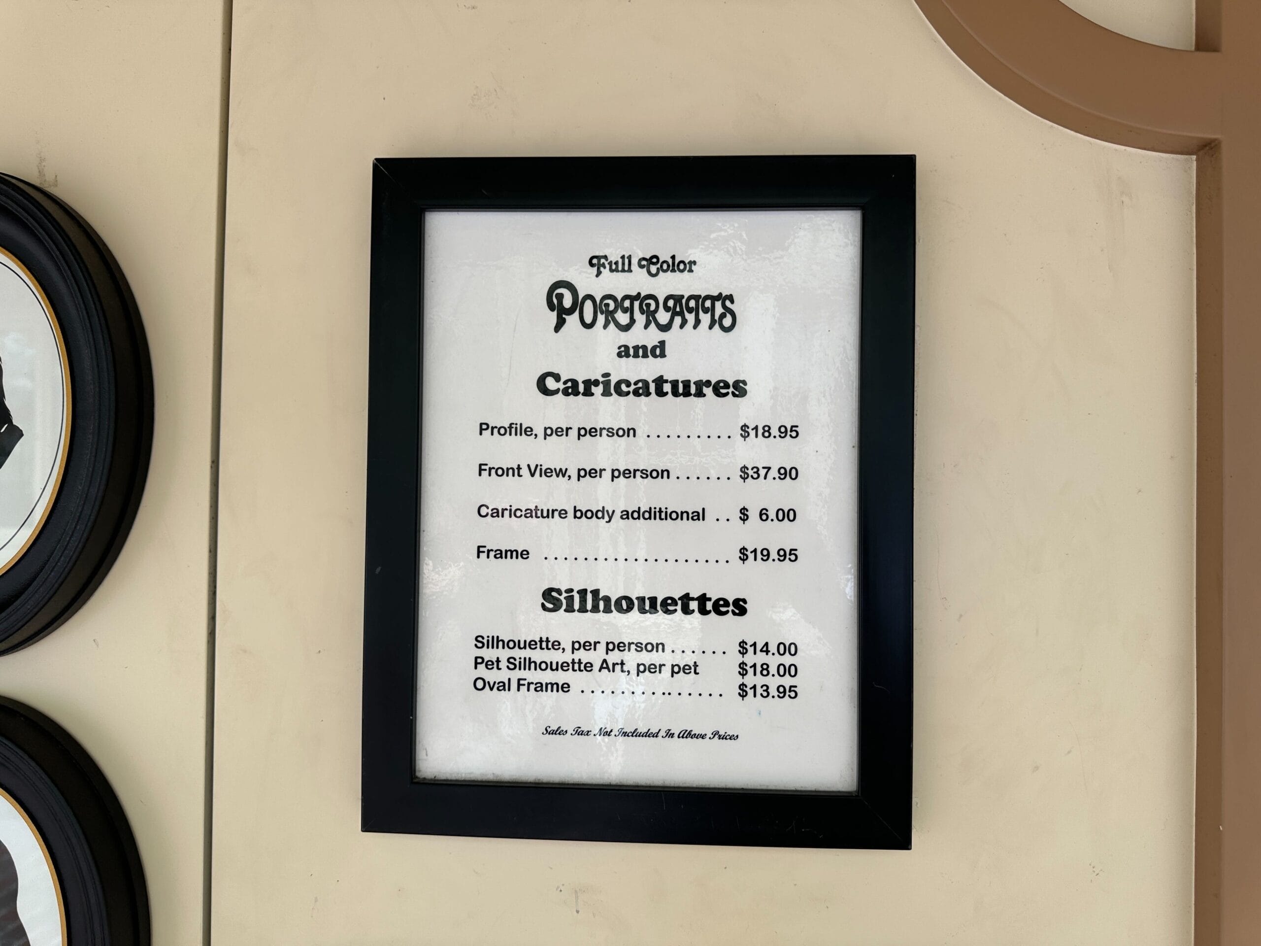 Framed price list for full-color portraits, caricatures, and silhouettes—with various styles—hangs on the wall.