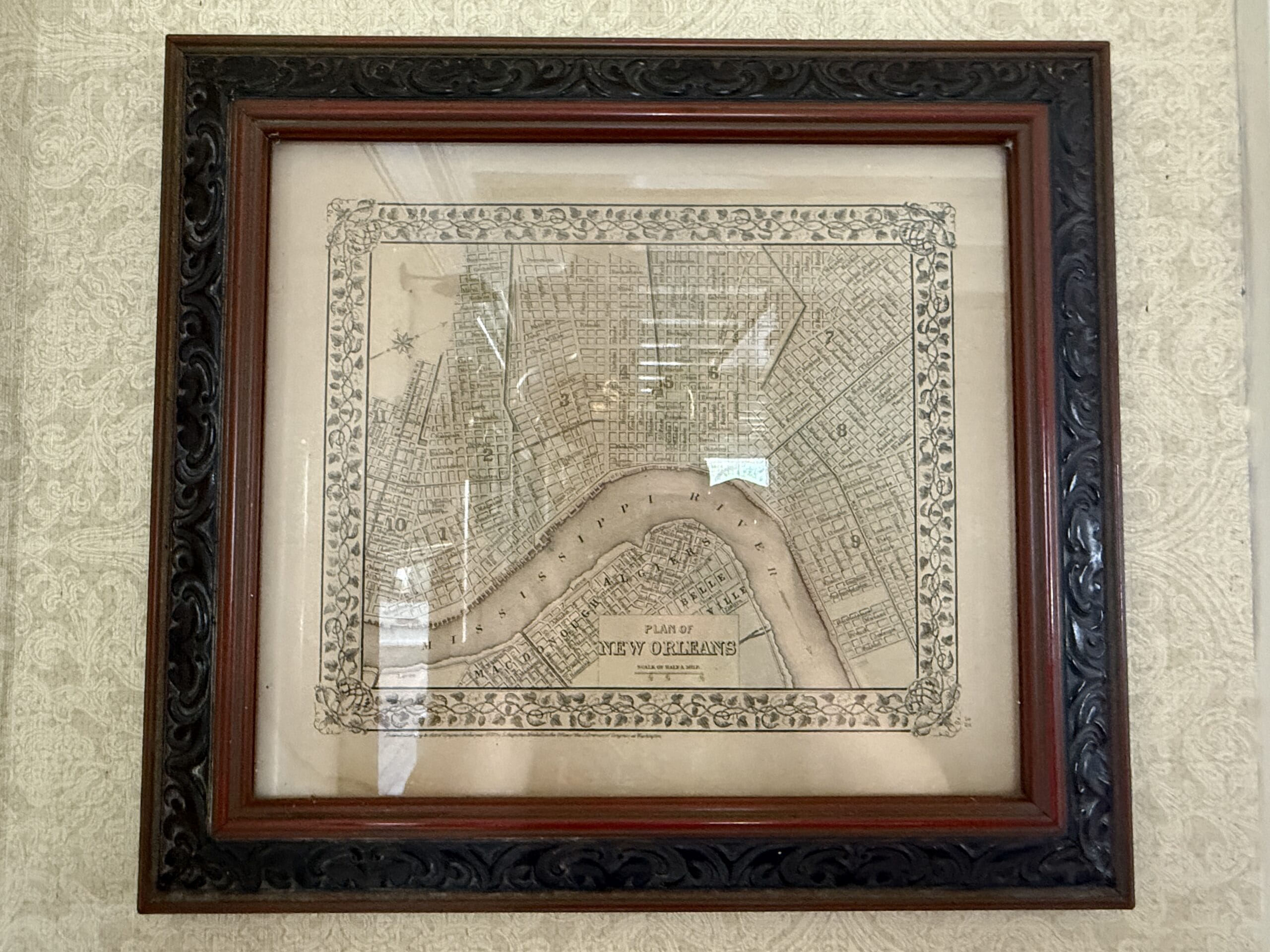 Framed vintage map of New Orleans, hanging on a patterned wall, reminiscent of the Magic Kingdom charm.
