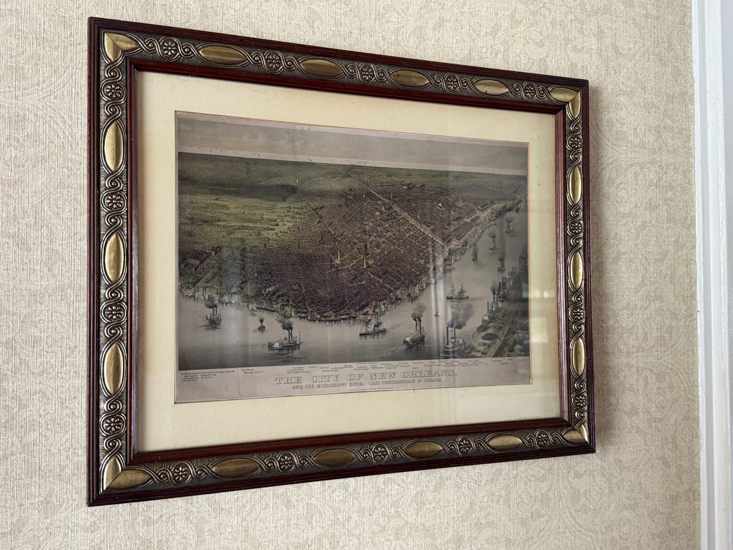 Framed vintage map of New Orleans, reminiscent of the Liberty Square Riverboat, on a textured wallpapered wall.