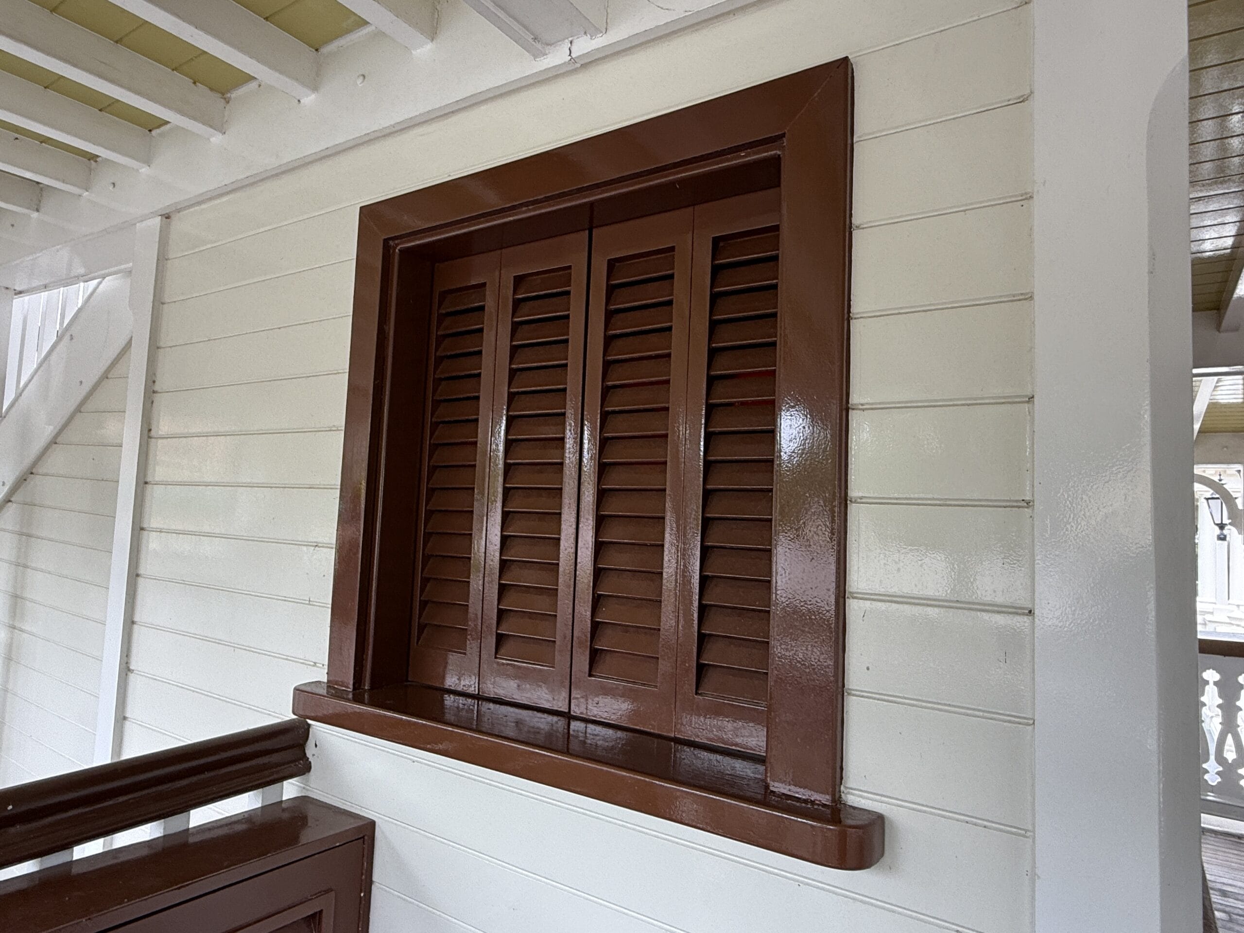 Brown wooden louvered window on a cream paneled wall, reminiscent of Liberty Square Riverboat at Magic Kingdom.