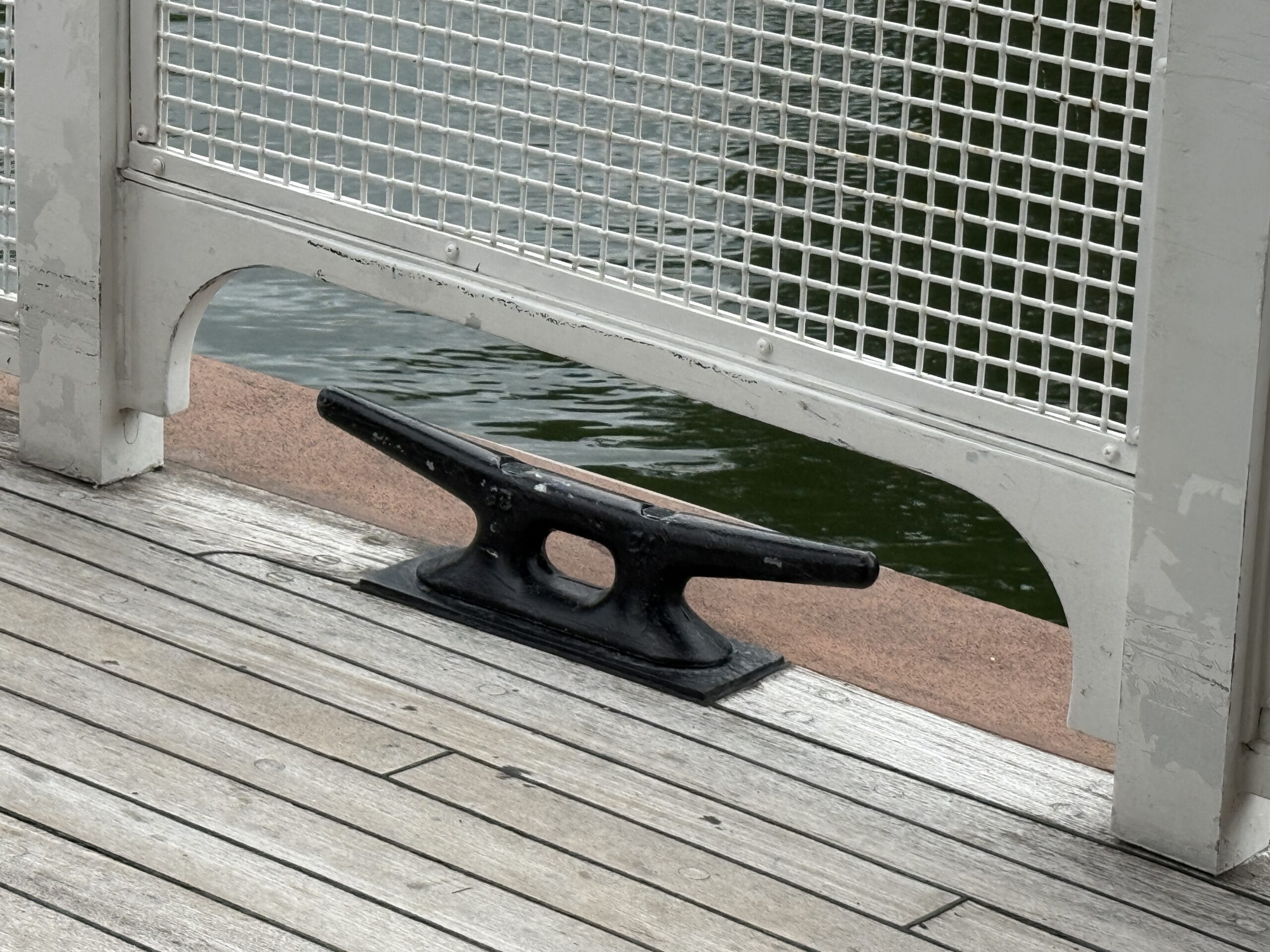 A black dock cleat is mounted on a wooden pier near the Liberty Square Riverboat at Magic Kingdom.
