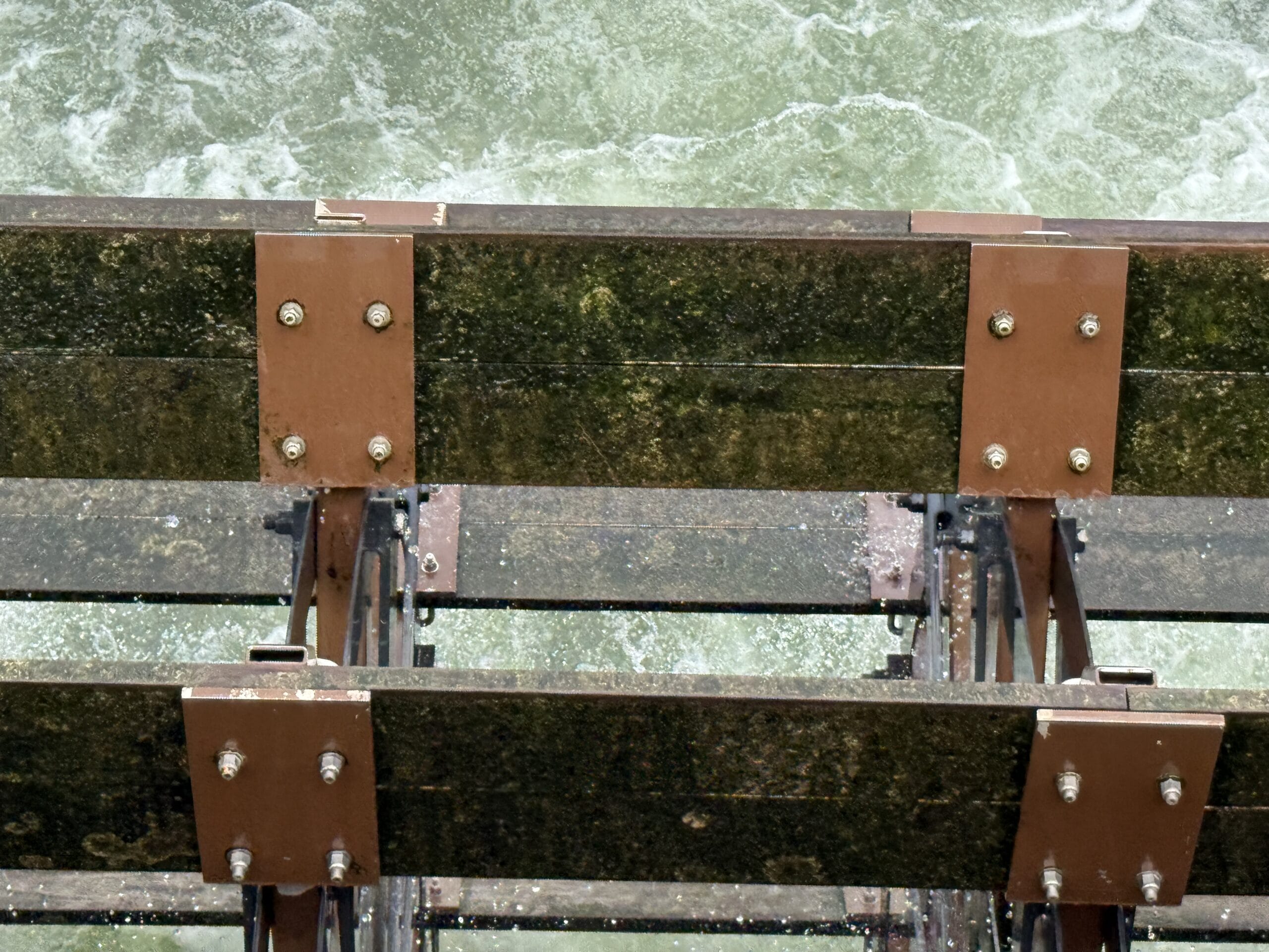 Close-up of a rusty water wheel at Liberty Square Riverboat, partially submerged in churning water at Magic Kingdom.
