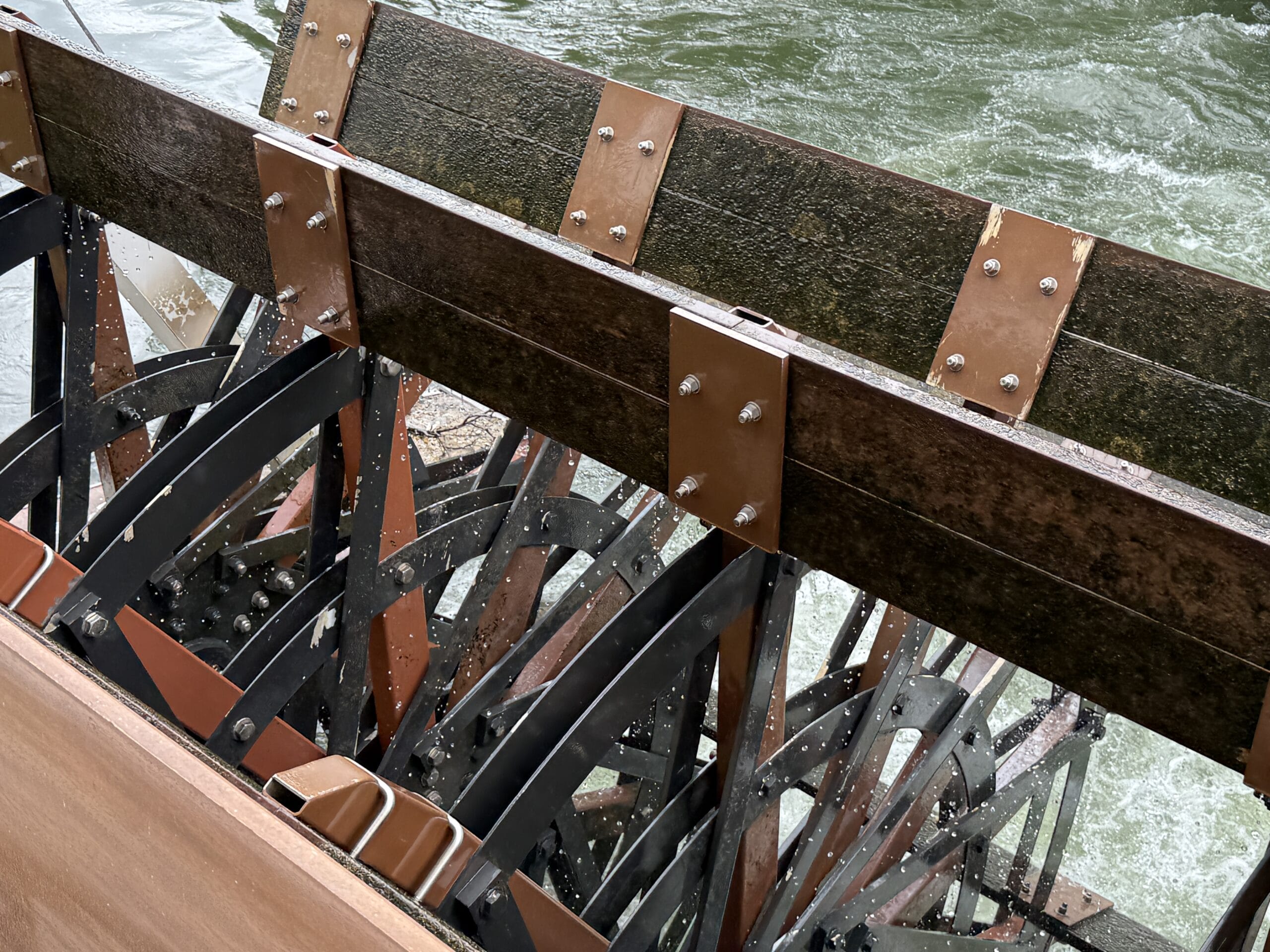 Close-up of the Liberty Square Riverboat paddle wheel turning in water, splashing below at Magic Kingdom.