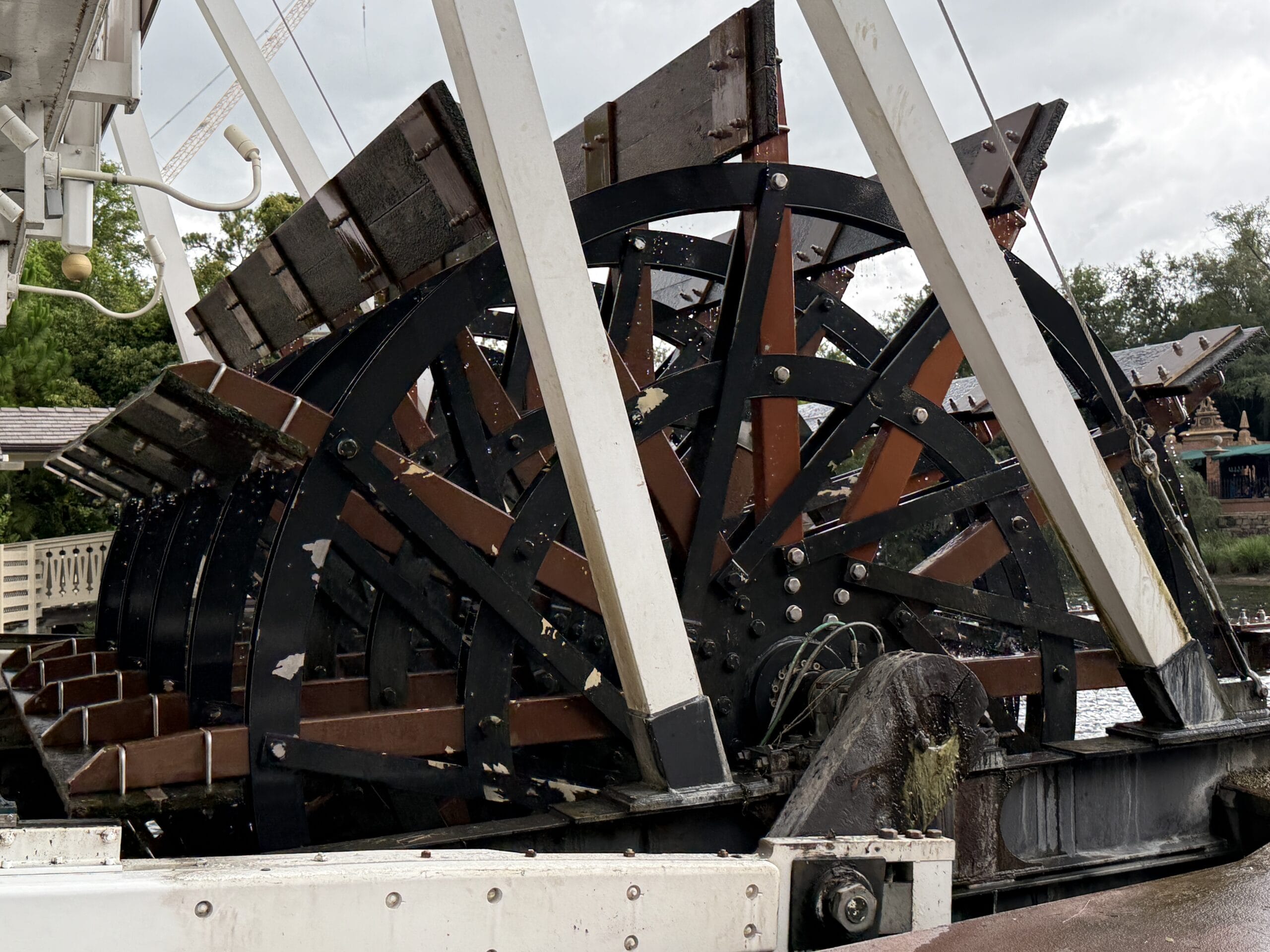 Close-up of the Liberty Square Riverboat's large black and brown paddlewheel at Magic Kingdom, with metal spokes and wooden slats.