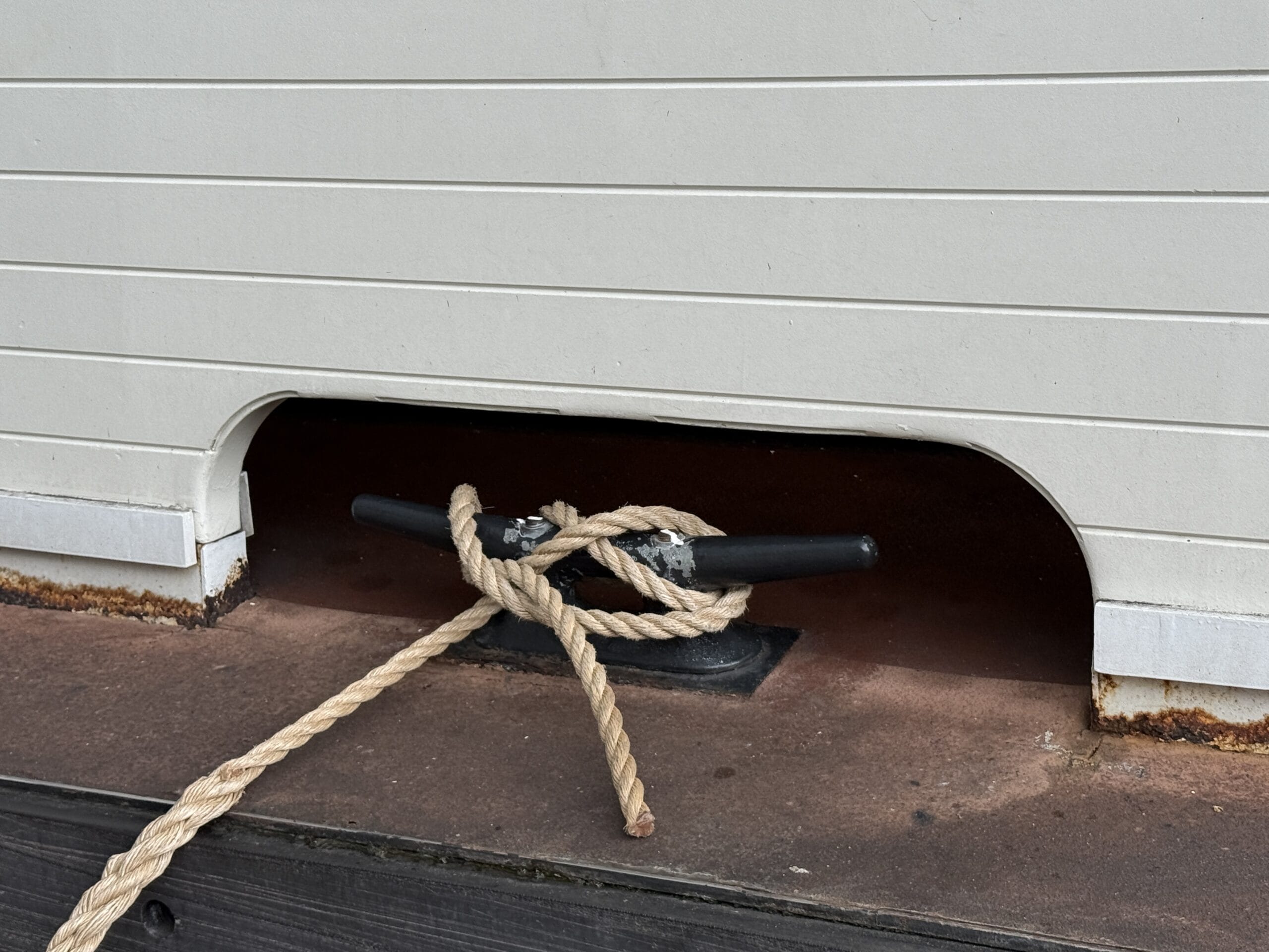 A knotted rope tied to a metal cleat beneath a cutout, like those on the Liberty Square Riverboat in Magic Kingdom.
