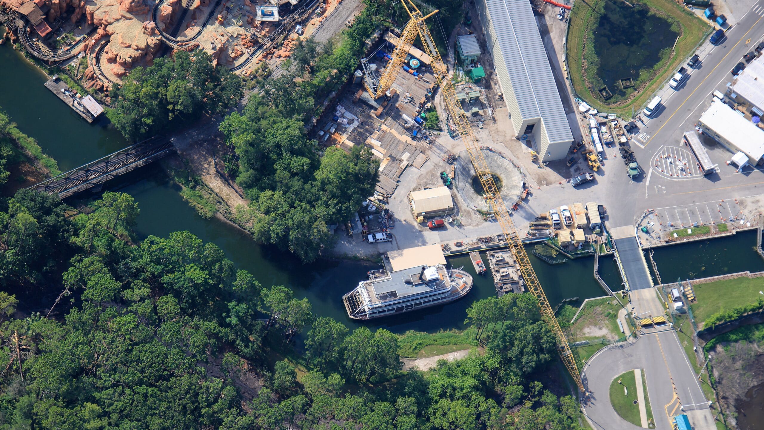 Aerial view of the Liberty Square Riverboat docked among trees, construction equipment, and nearby industrial buildings.