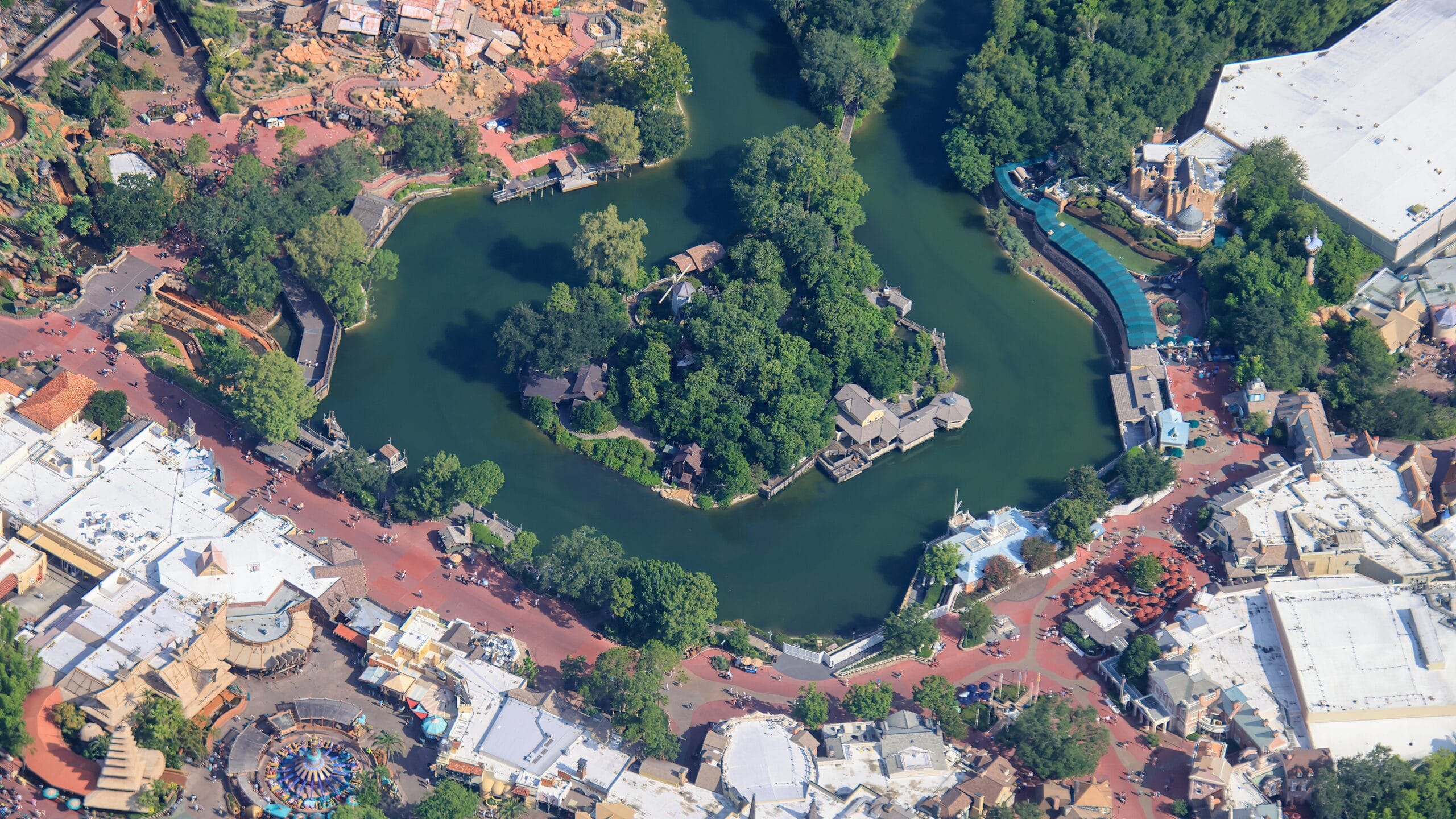 Aerial view of Magic Kingdom with Liberty Square Riverboat, island, trees, and buildings clustered around winding pathways.