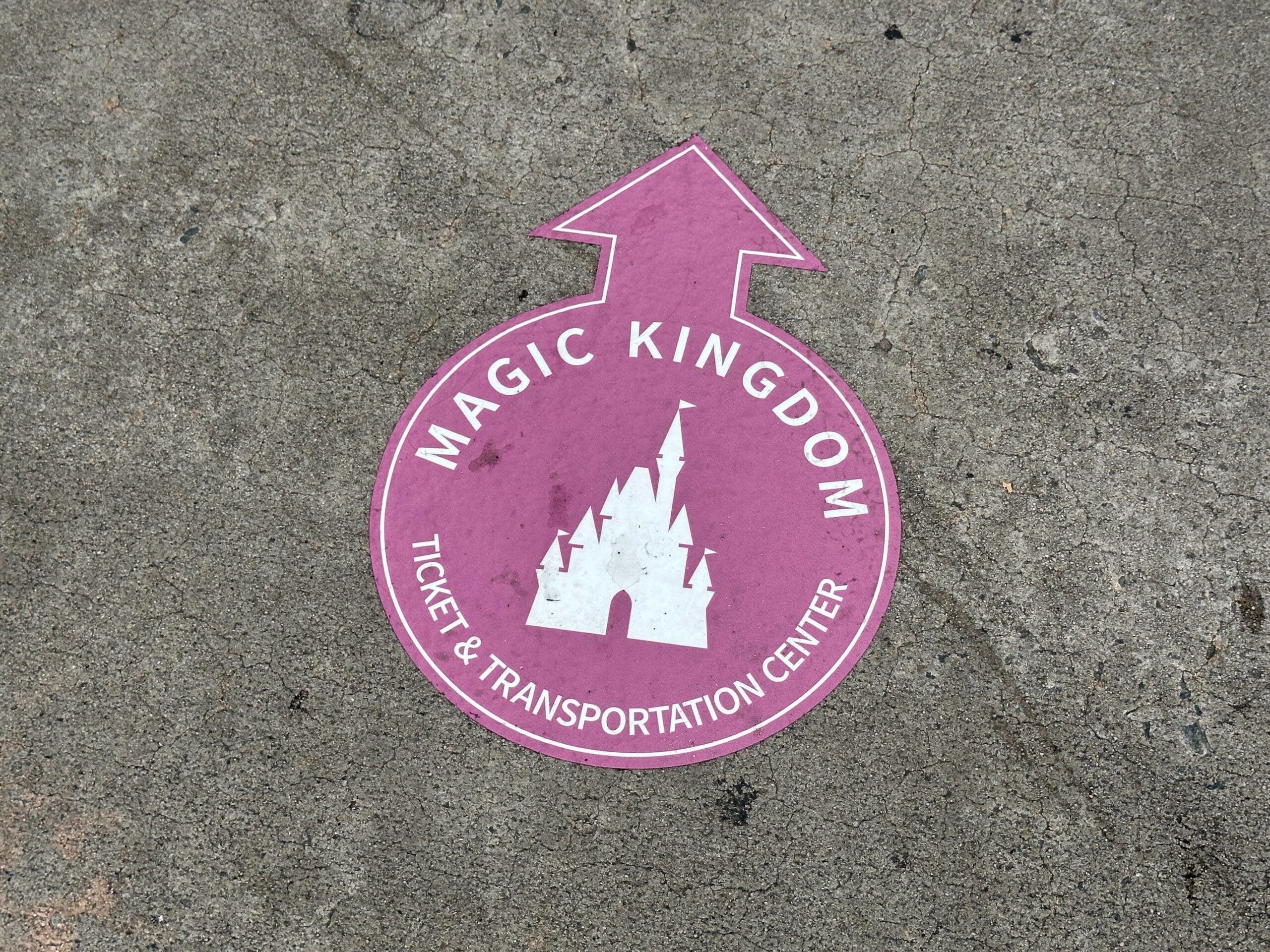 Purple ground sign with castle icon and arrow, guiding to Parking Lot and Transportation and Ticket Center.