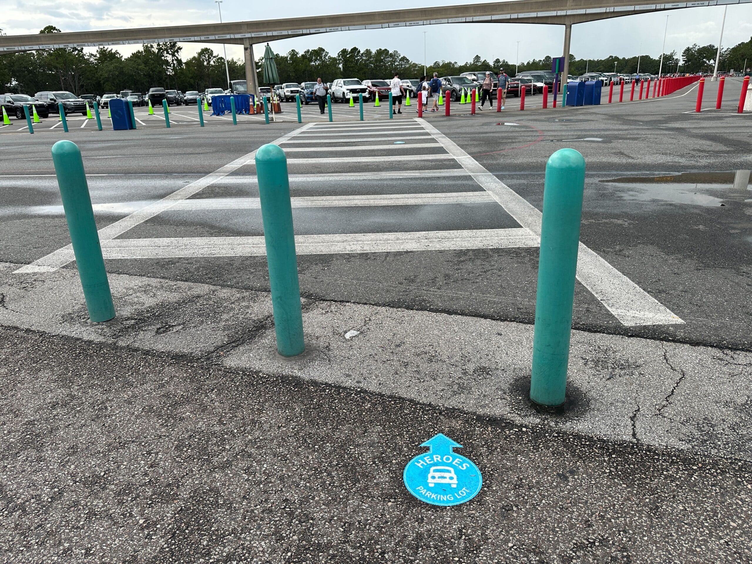 Three teal posts block a crosswalk in the Transportation and Ticket Center; Parking Lot Decals mark the ground.