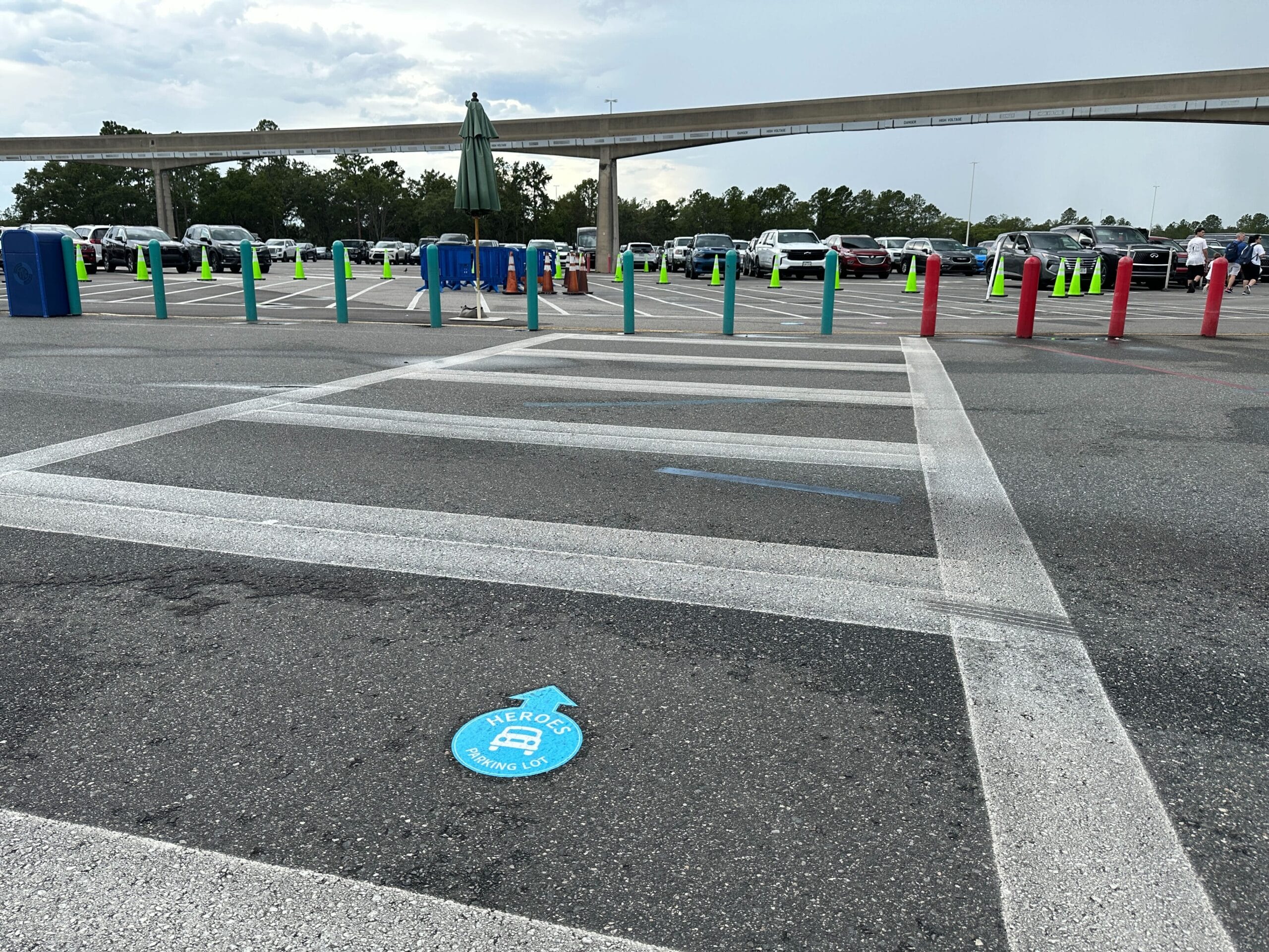 Large parking lot with parking lot signs, colorful poles, and a blue "Heroes" section marker at the Transportation and Ticket Center.
