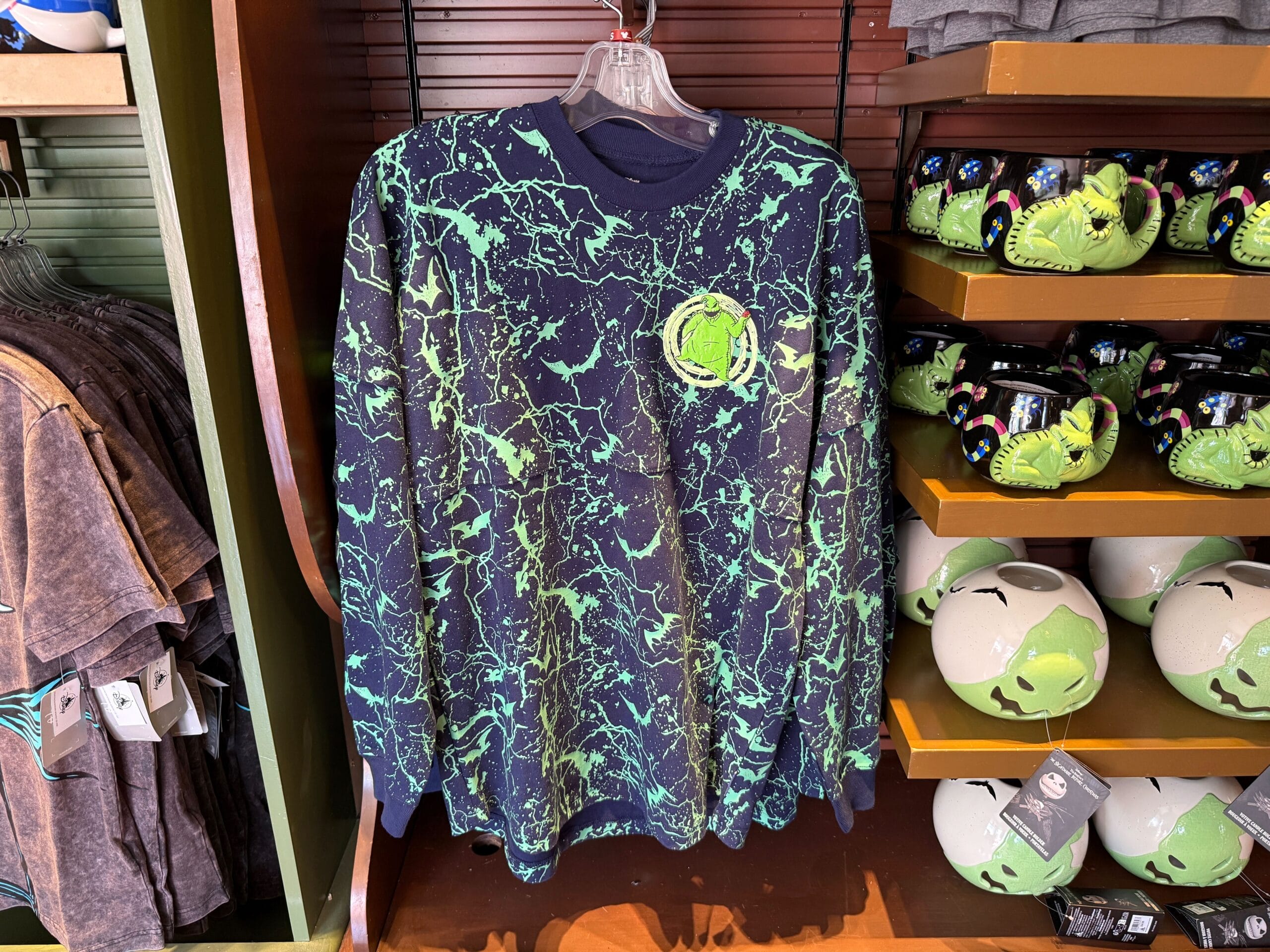A black long-sleeve shirt with green splatter and Hulk logo, displayed near new Nightmare Before Christmas merchandise.