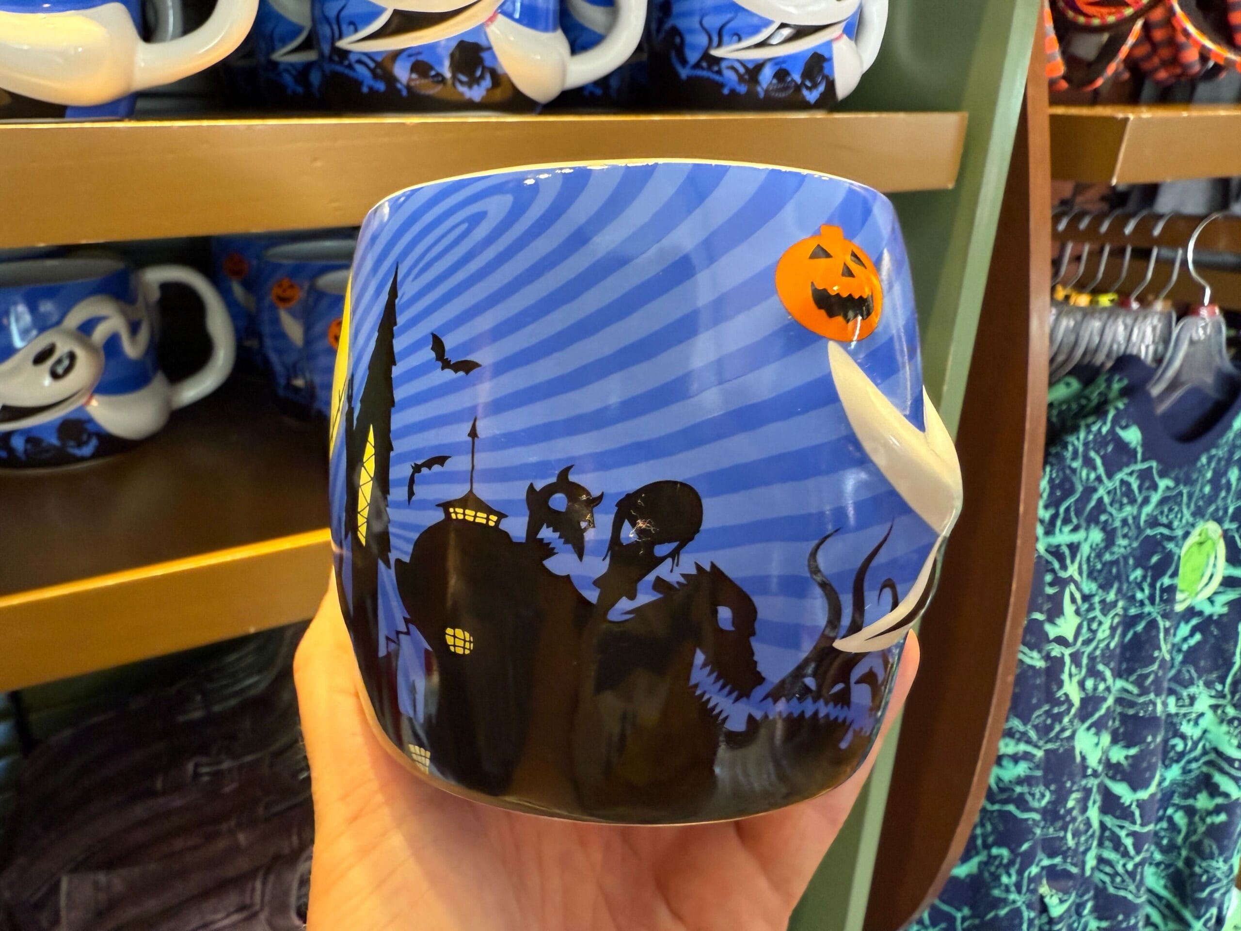 A Halloween mug with a blue background, spooky silhouettes, bats, and a pumpkin—perfect for Nightmare Before Christmas fans.